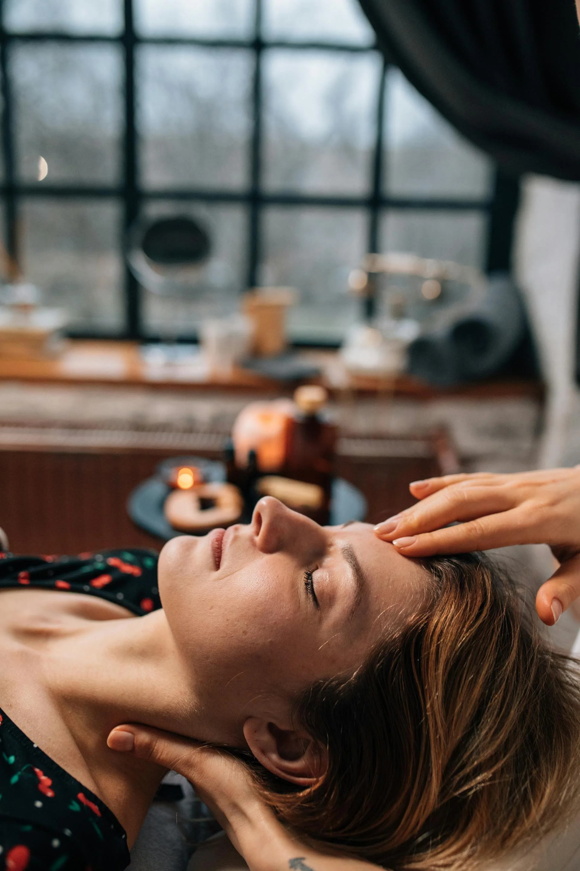 A woman receiving a massage or facial treatment while lying down with eyes closed in a spa or wellness center.