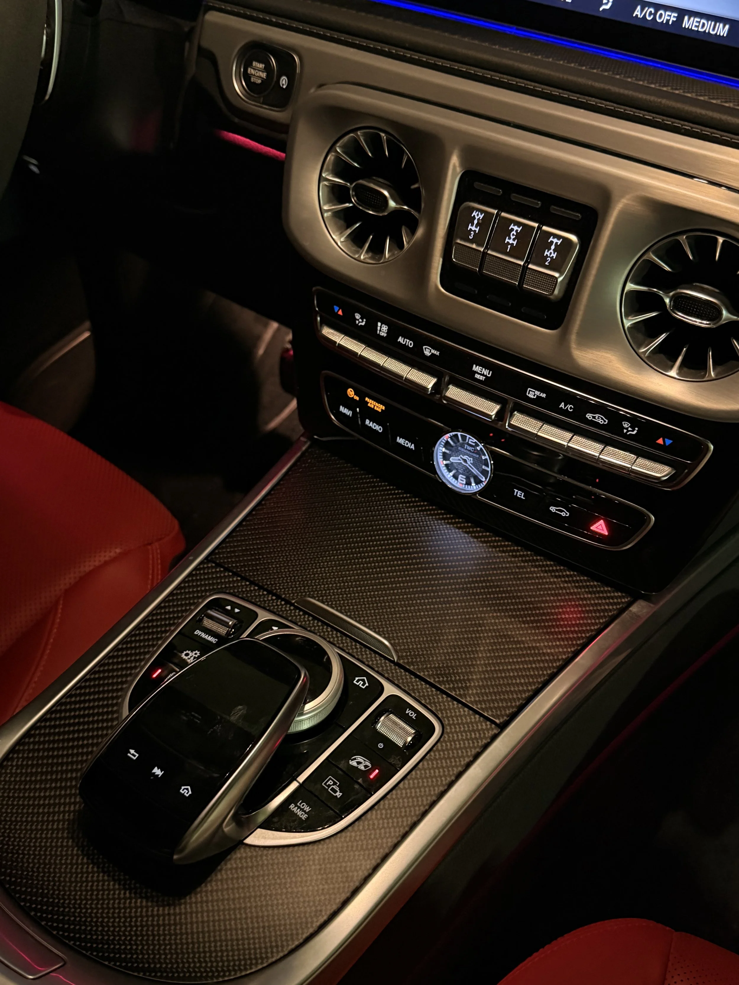 The interior of a luxury car with a diesel engine. The dashboard has air vents, climate controls, a clock, and various buttons for multimedia and navigation. The center console features a touchpad, rotary dial, and additional controls.