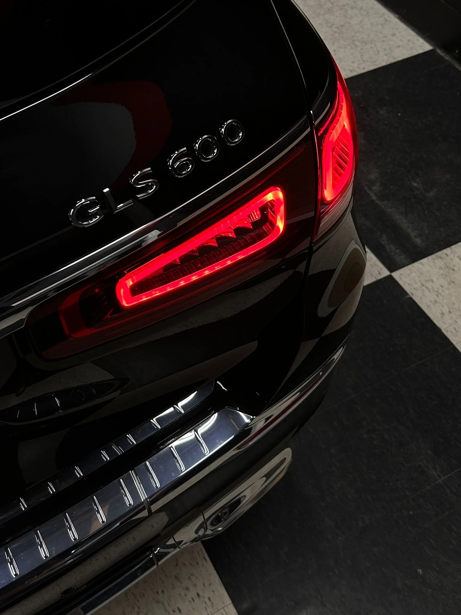 The rear end of a black Mercedes-Benz GLC 300 with illuminated taillights and chrome accents.