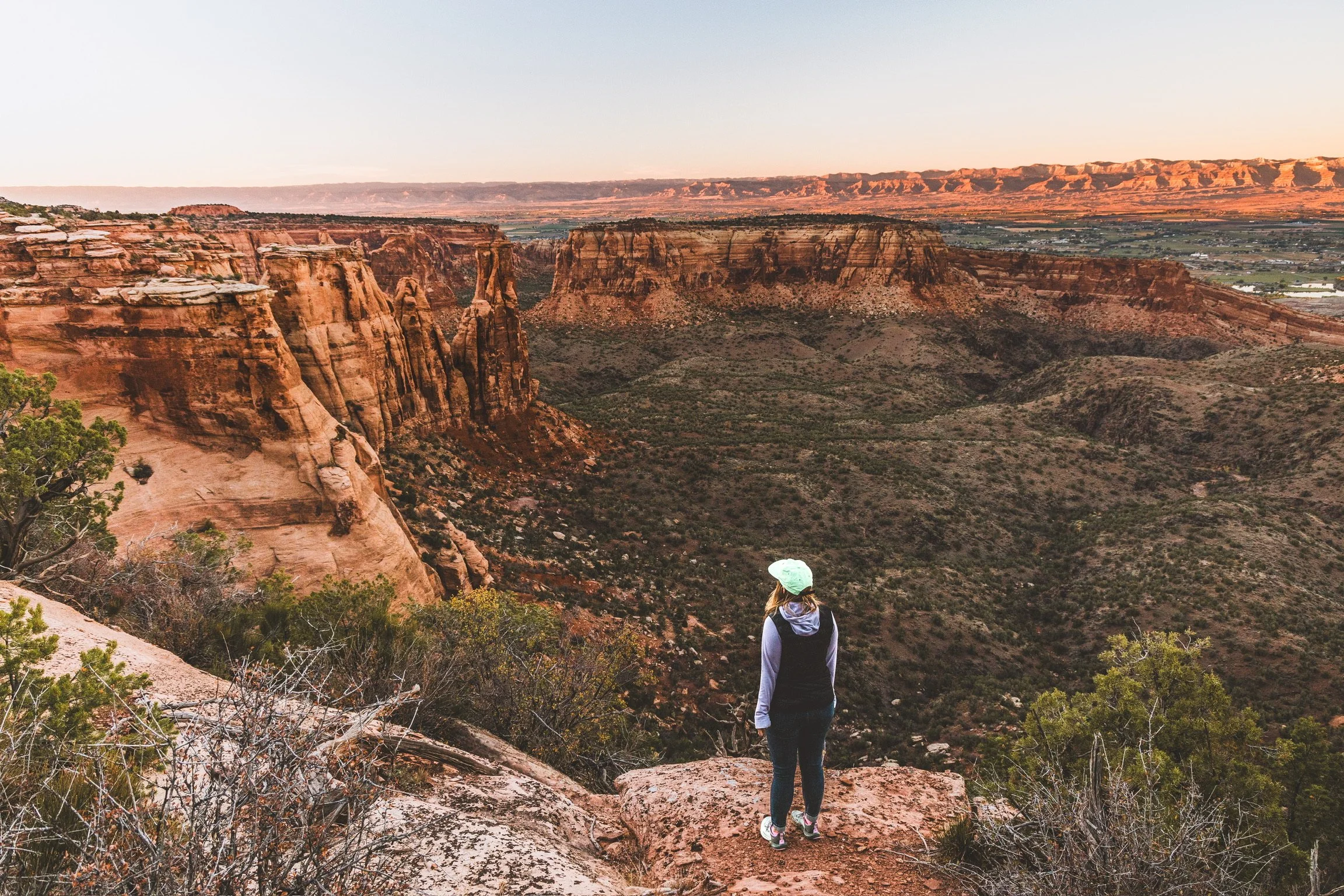Caley Van Cleave, contemporary landscape painter, overlooking the Colorado National Monument at dusk chasing the golden hour in the desert in Fruita, CO. Photo credit to Kevin Ingham.