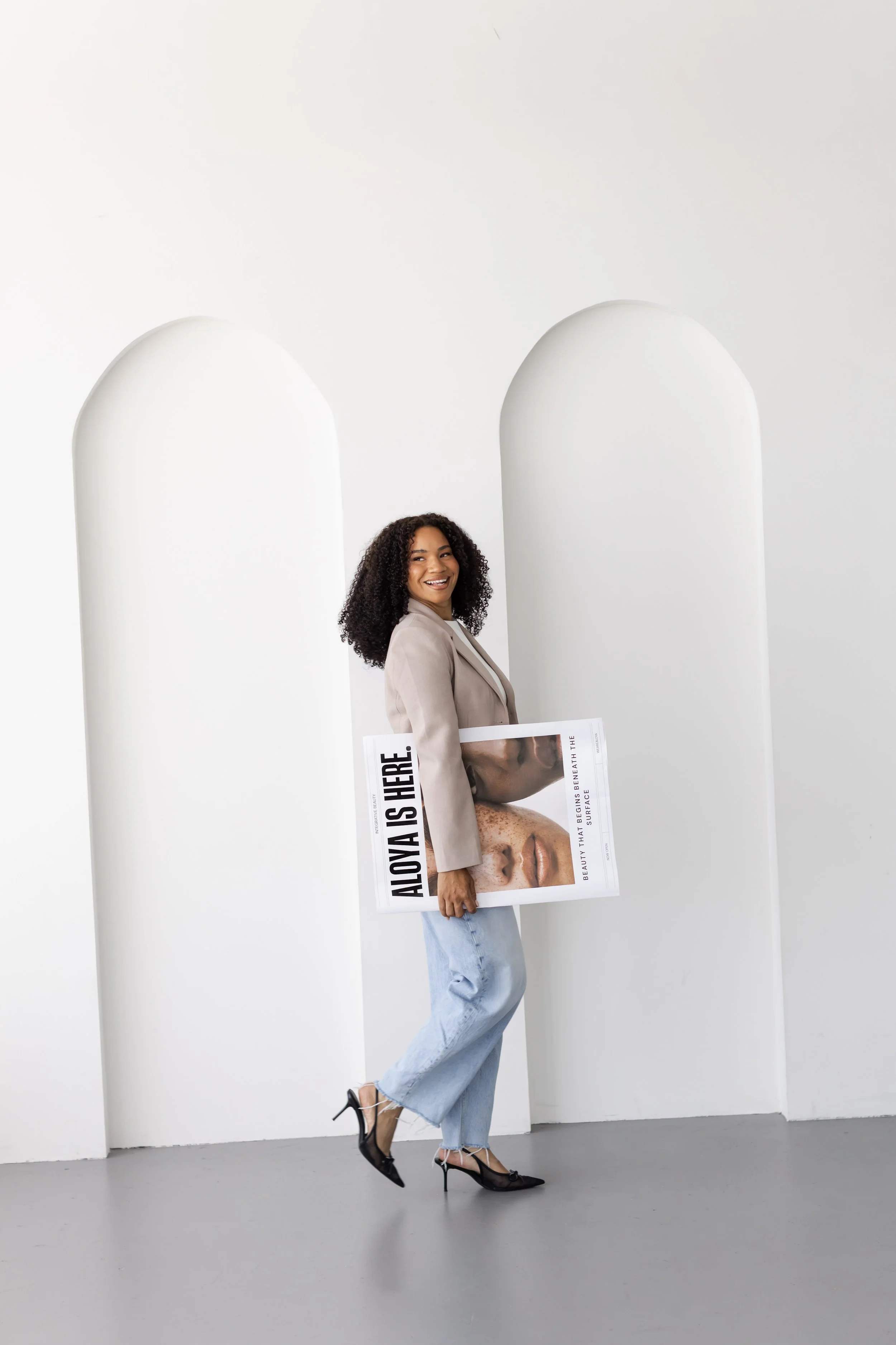 Branding photoshoot in Toronto for a beauty and wellness brand featuring model holding campaign poster in an editorial setting.