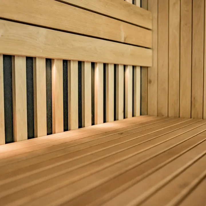 Close-up of wooden slats on a sauna wall and bench with warm lighting