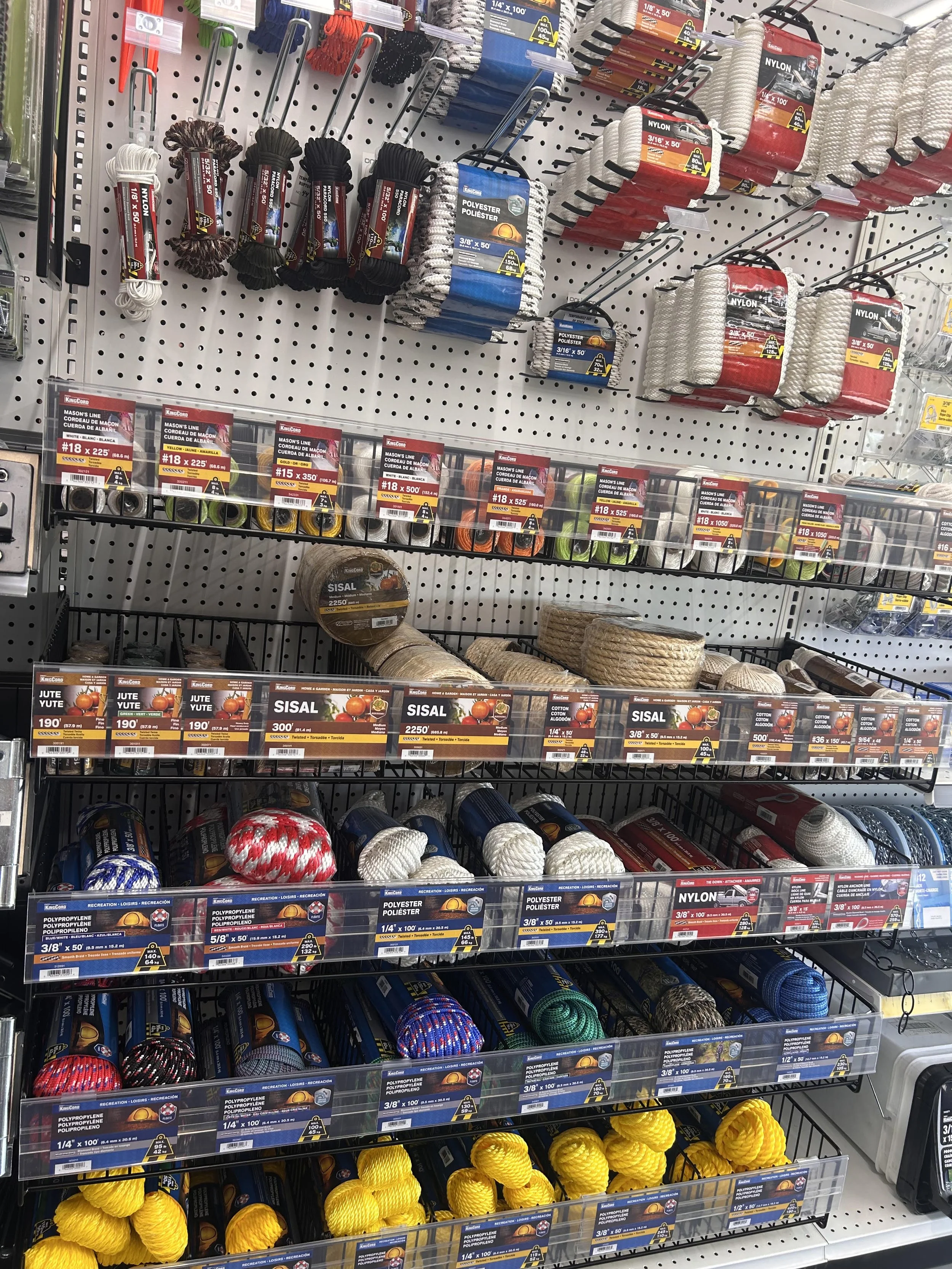 Store shelf displaying various types of rope, cord, and twine in different colors and sizes, with labels indicating specifications and prices.