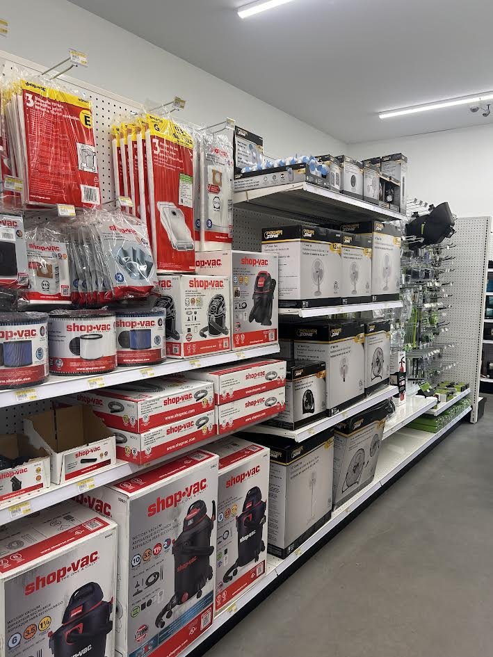 Store aisle with vacuum cleaners, fans, and home appliances on shelves.