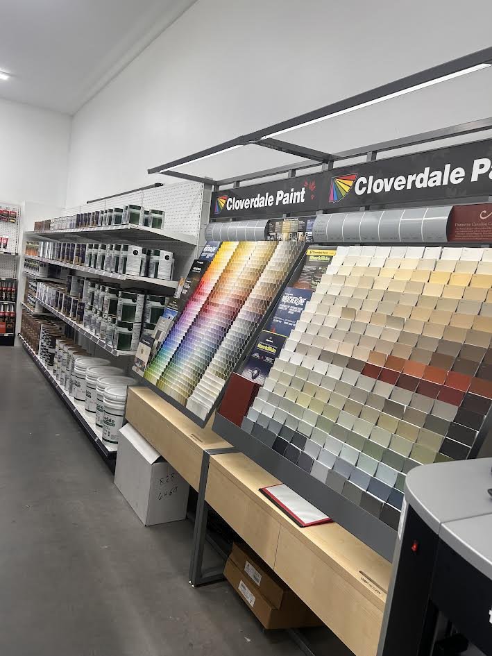 Display of paint color samples and color swatches at a hardware store aisle.