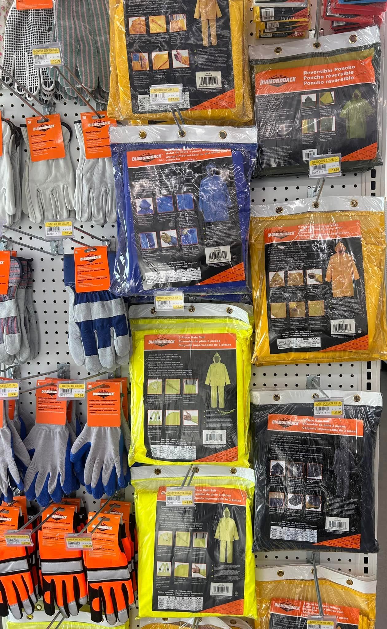Various rain gear products including gloves, rain suits, and ponchos hanging on store pegboard.