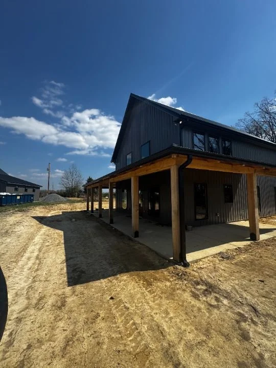 Timber frame building with covered porch and metal roof on a rural property