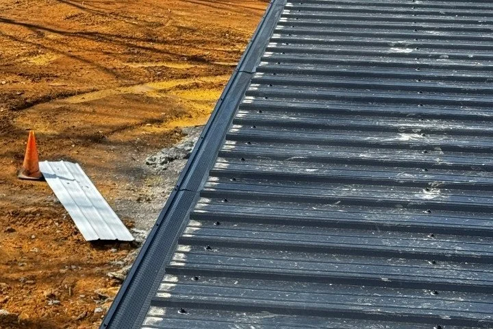 Close-up of a dark metal roof edge with new gutter install