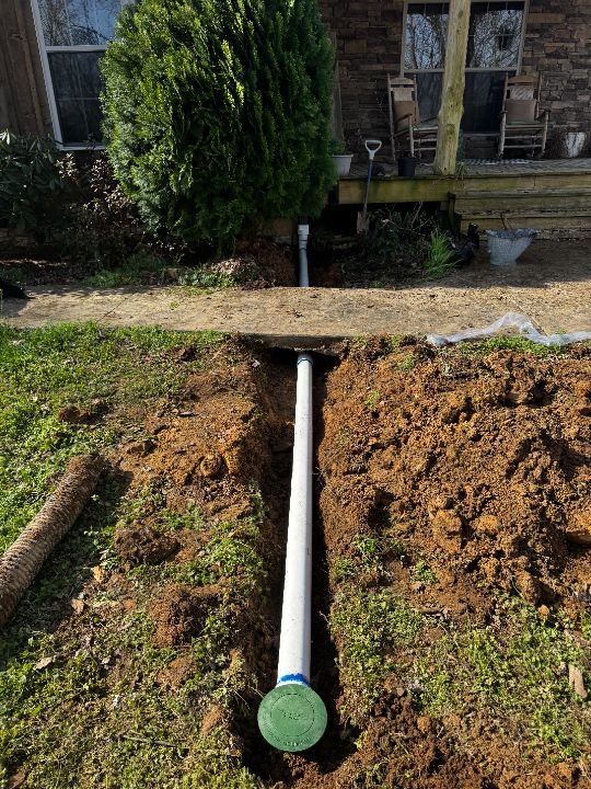 White PVC underground drain pipe laid in an open dirt trench
