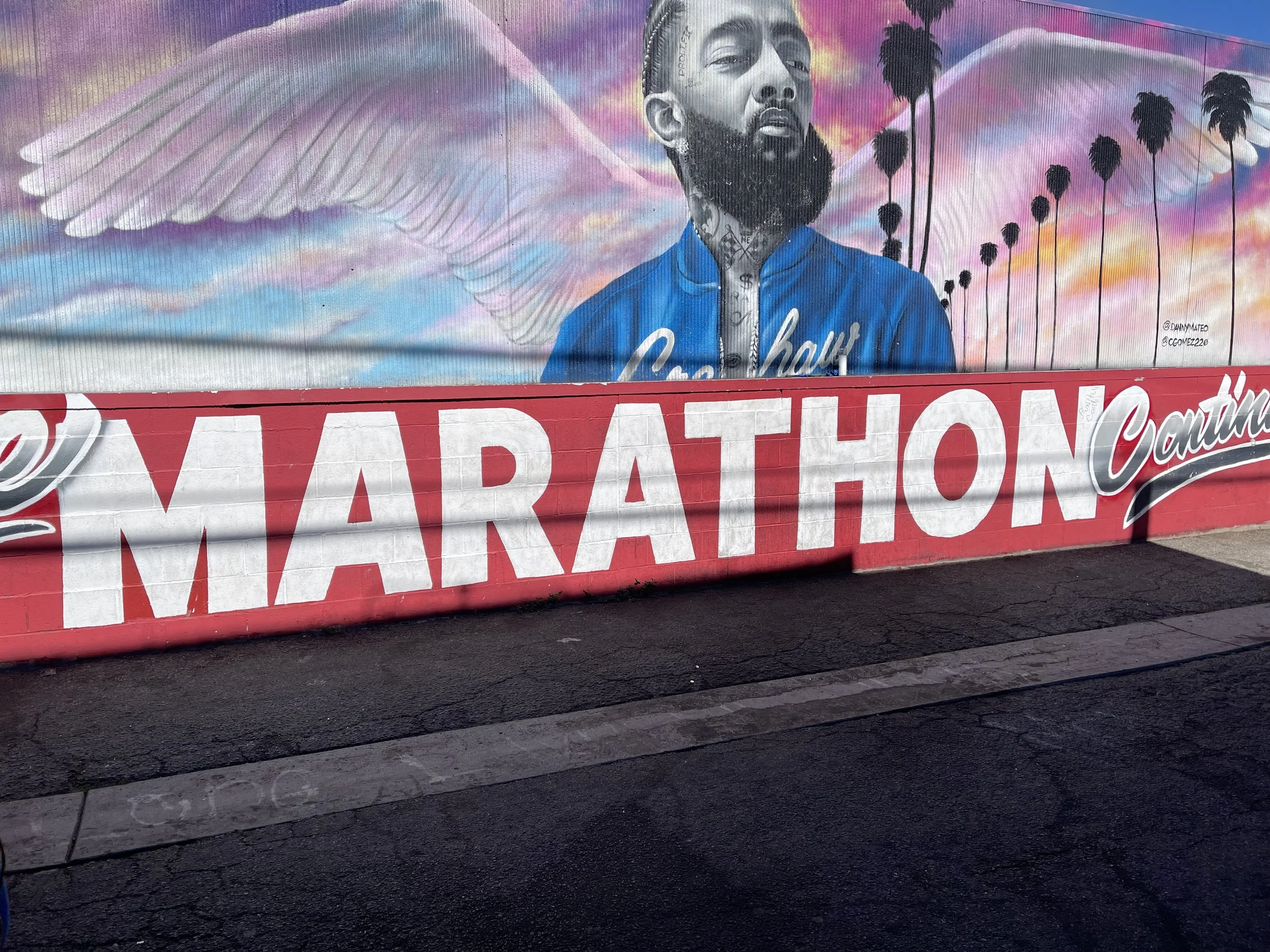 Murals featuring a portrait of a man with a beard, palm trees, angel wings, and a colorful sky in the background, with a red banner reading 'Marathon'.