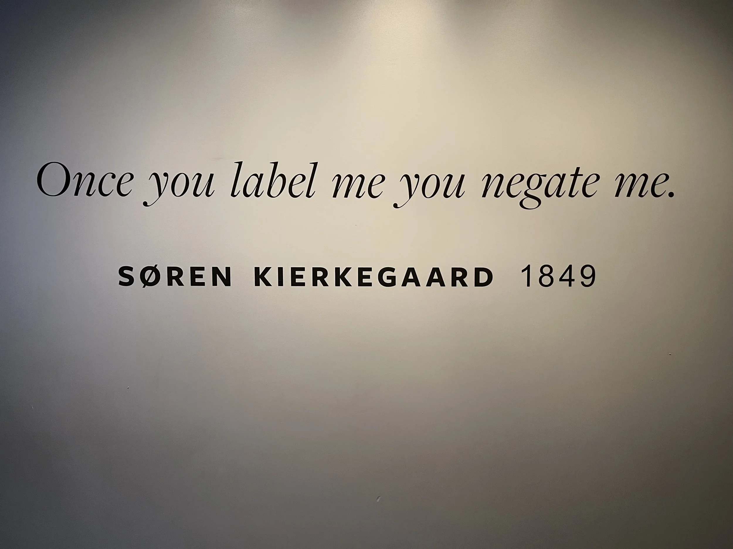 Inspirational quote on a wall: 'Once you label me you negate me.' by Søren Kierkegaard, 1849.