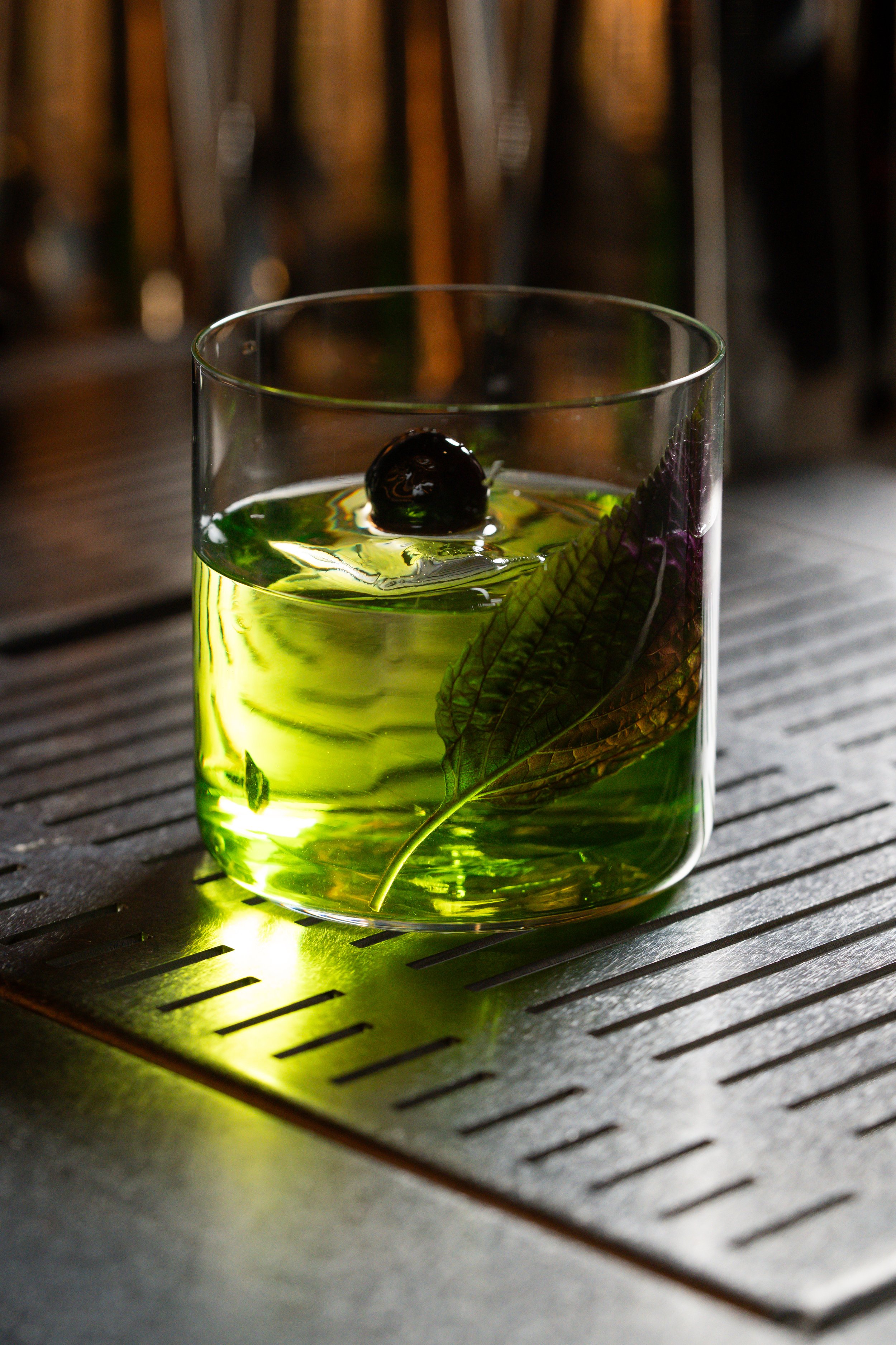 japanese clarified green cocktail with luxardo cherry and herbs