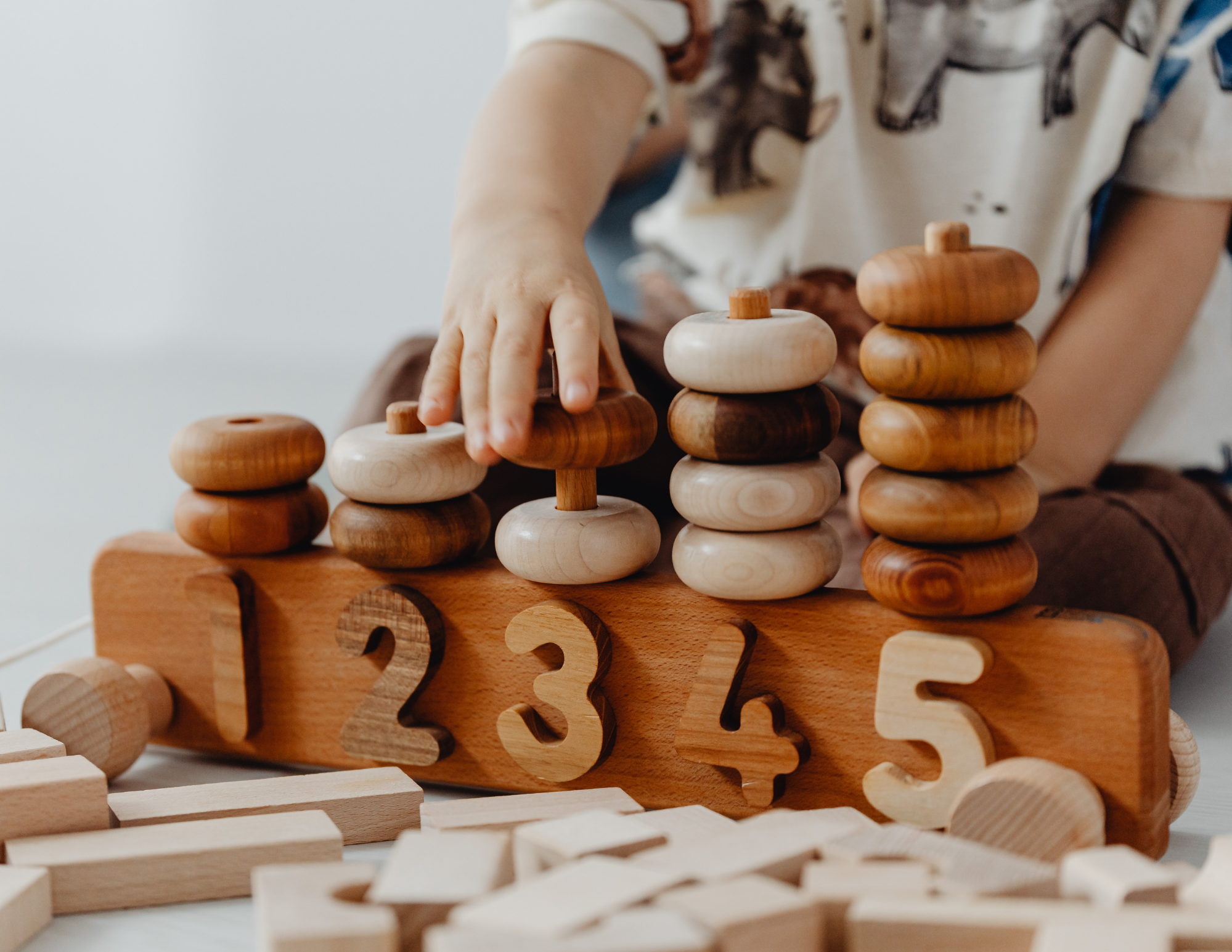 Child stacking wooden game pieces with letters.