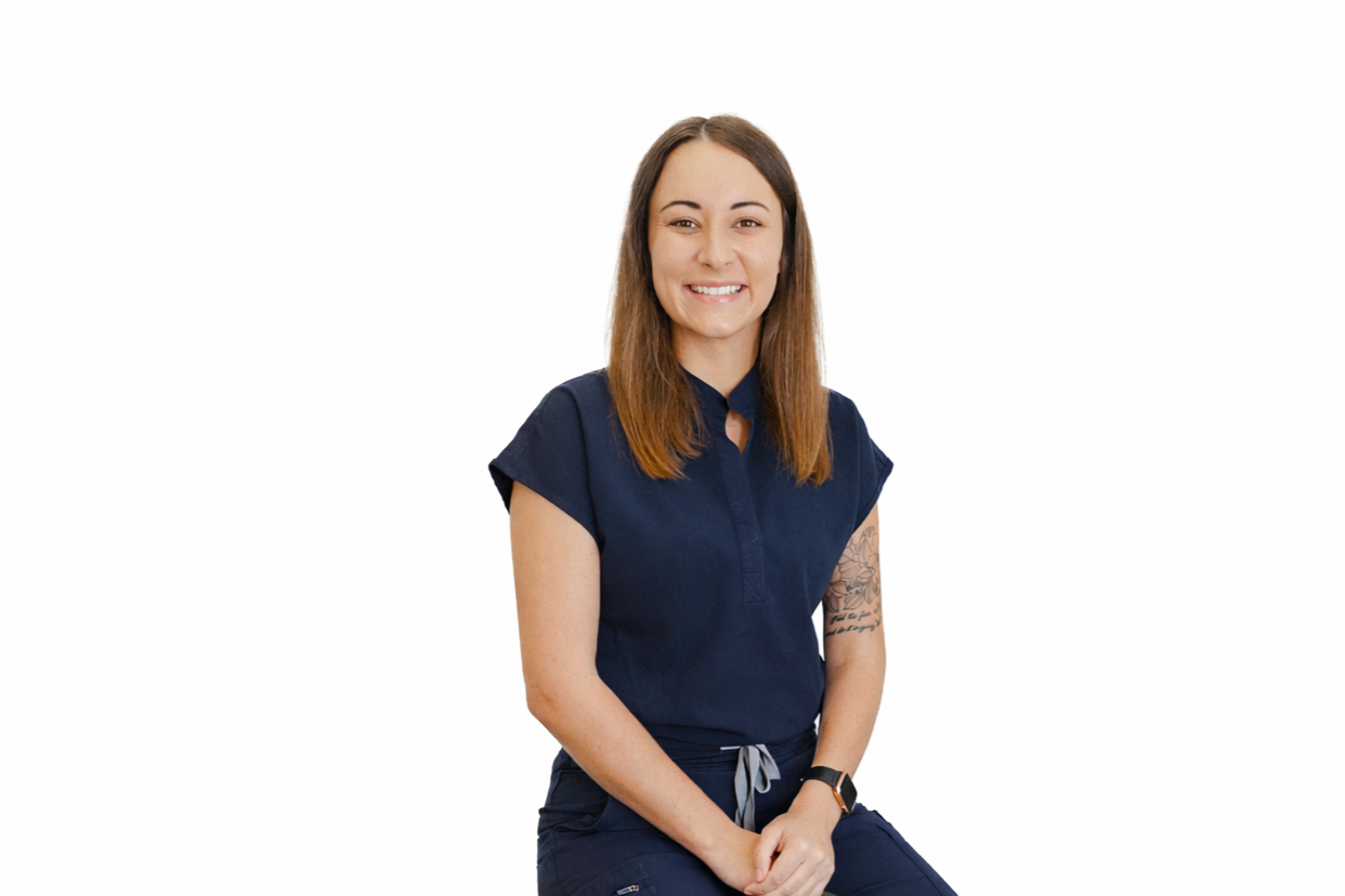 A young woman with shoulder-length brown hair wearing a navy blue uniform shirt, smiling, sitting against a white background.