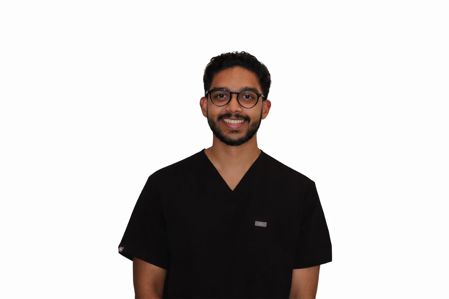 A smiling man with glasses and a beard wearing black medical scrubs against a white background.