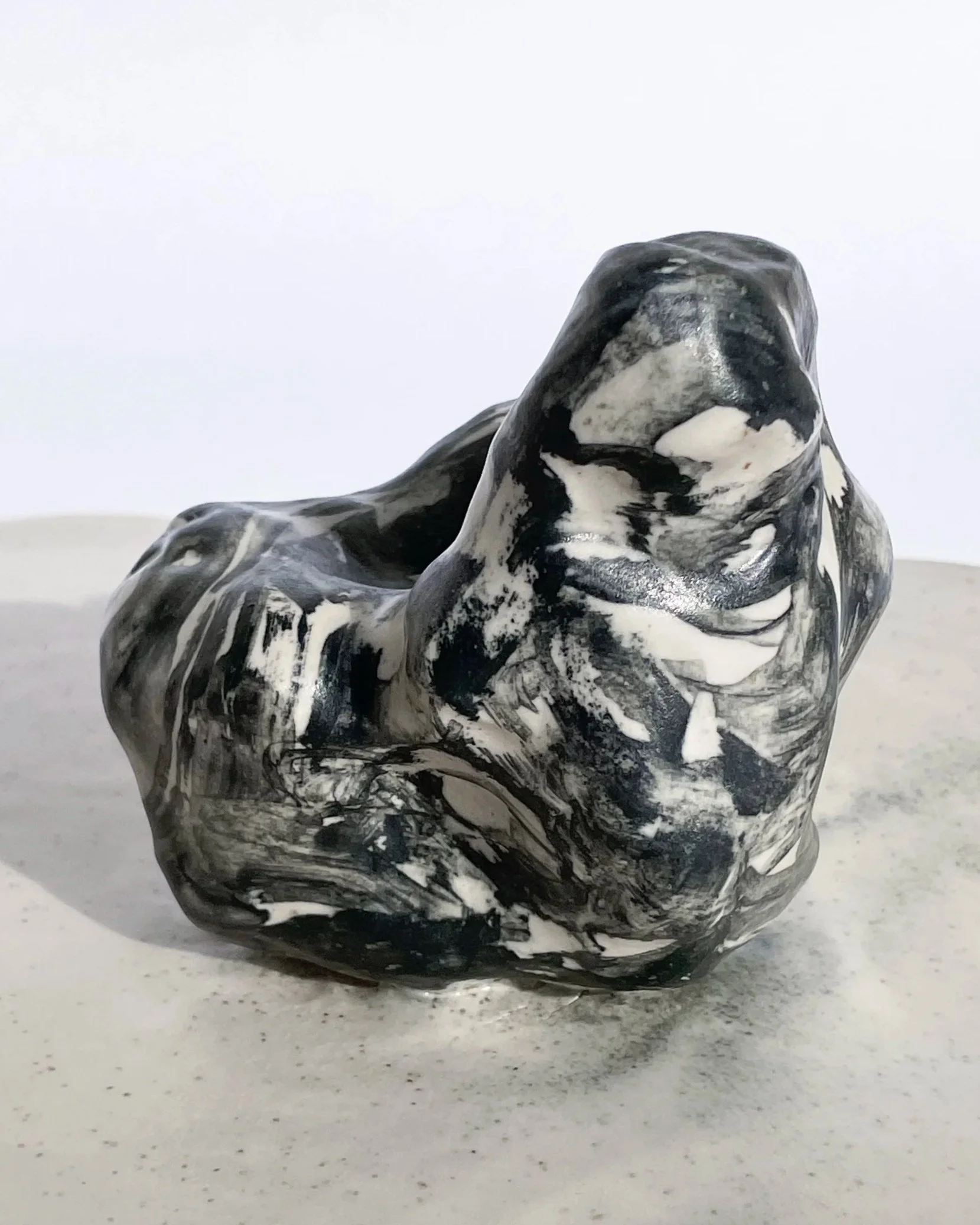 Black and white abstract marble sculpture on a white surface against a plain white background.