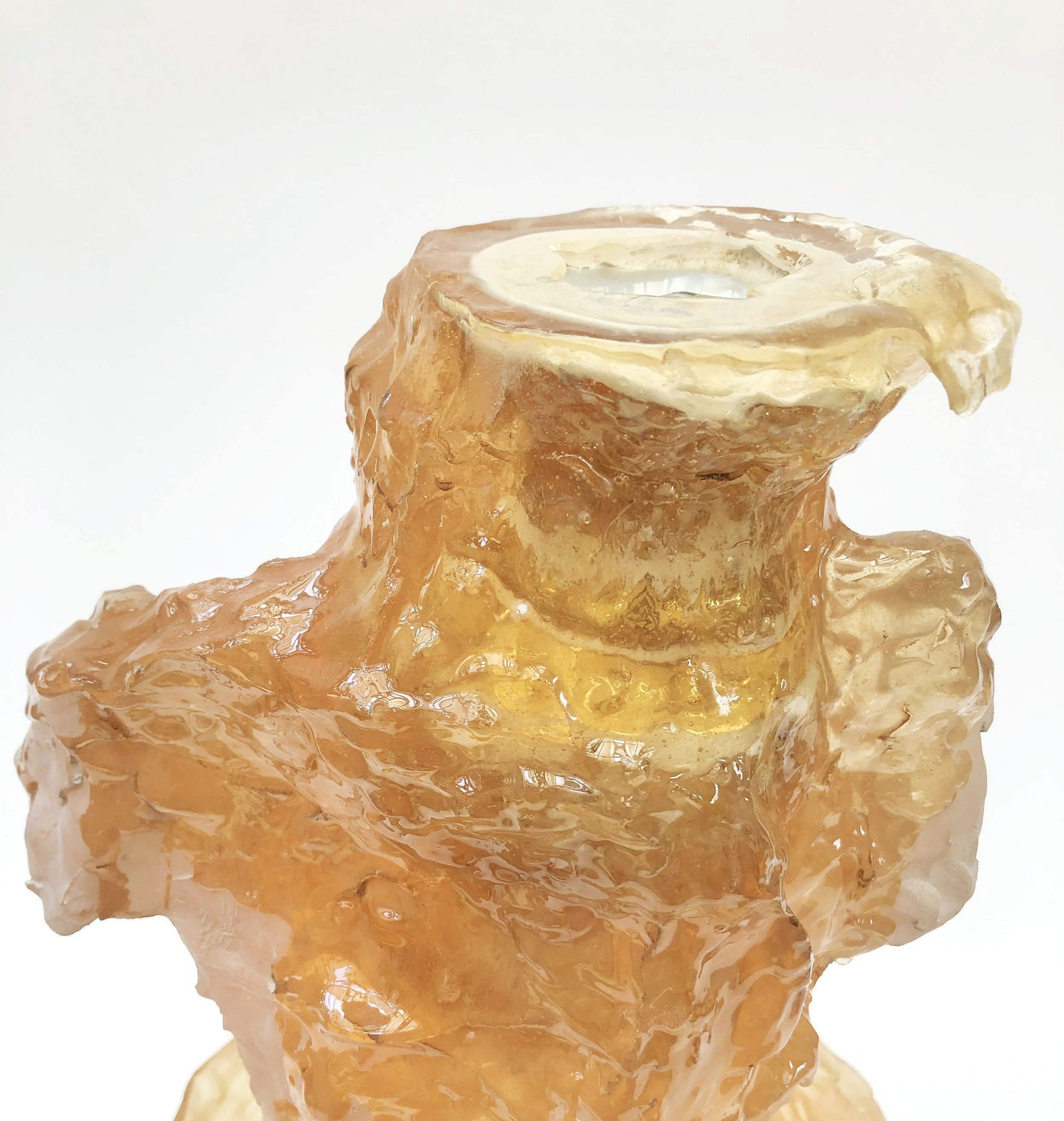 Close-up of a candle inside an ice sculpture, with melted wax dripping down the ice.