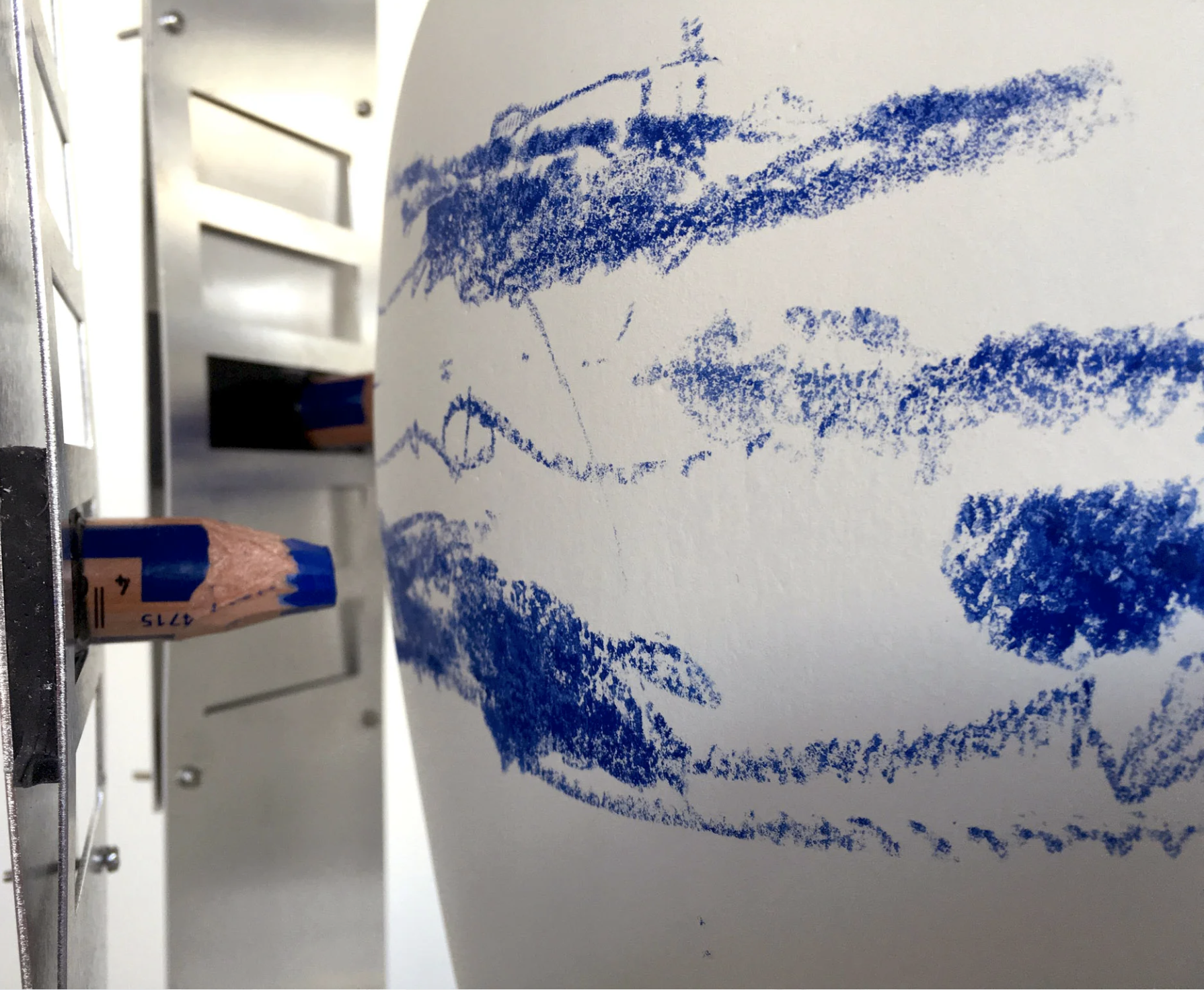 Blue pastel crayon on white paper creating a landscape with clouds and mountains.