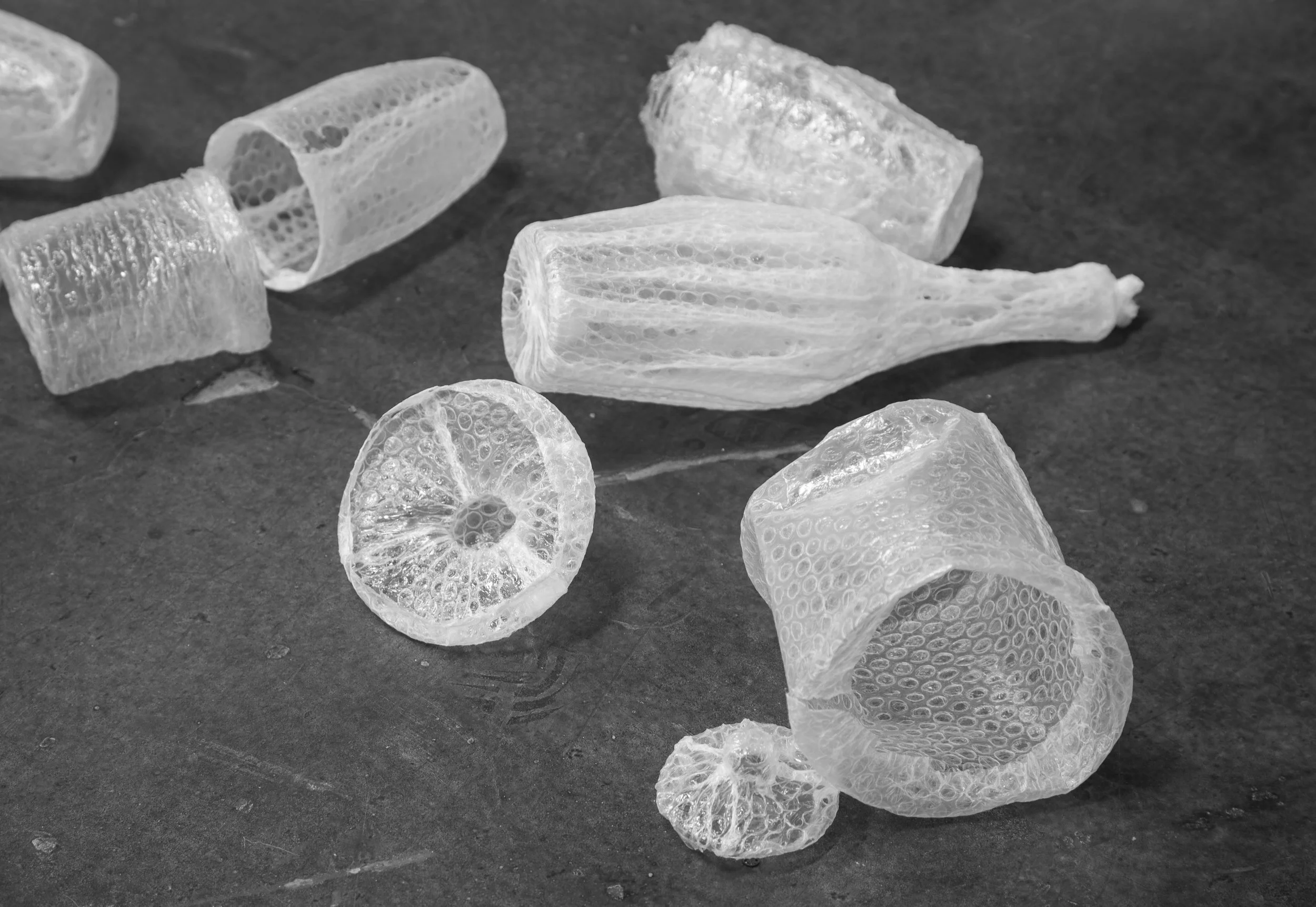 Several translucent soap curls on a dark surface, showing intricate bubble patterns.