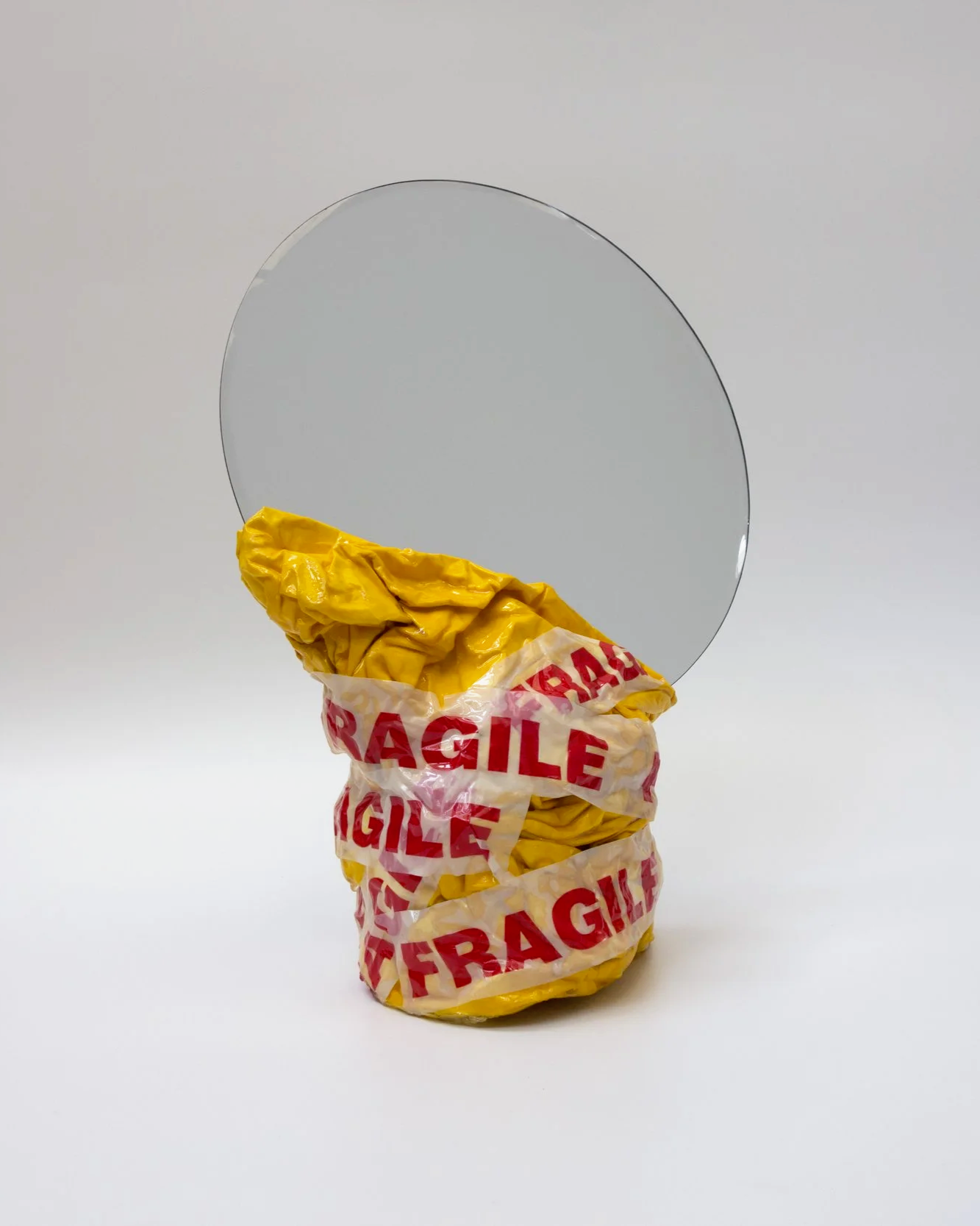 A broken mirror wrapped in yellow packing tape labeled 'Fragile'.