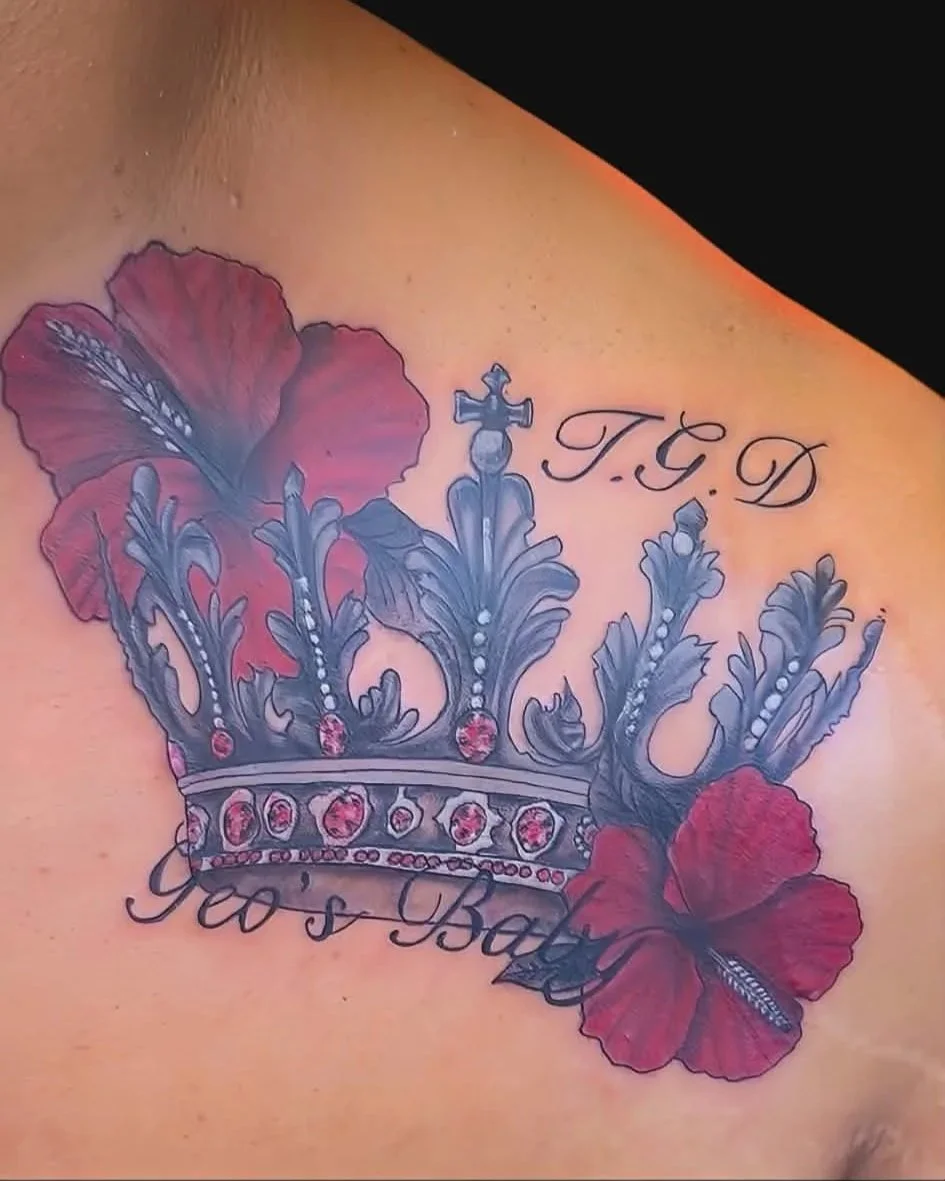 Tattoo of a crown with red and gray details, two red hibiscus flowers, and text reading "T.G.D" and "Yo's Baby".