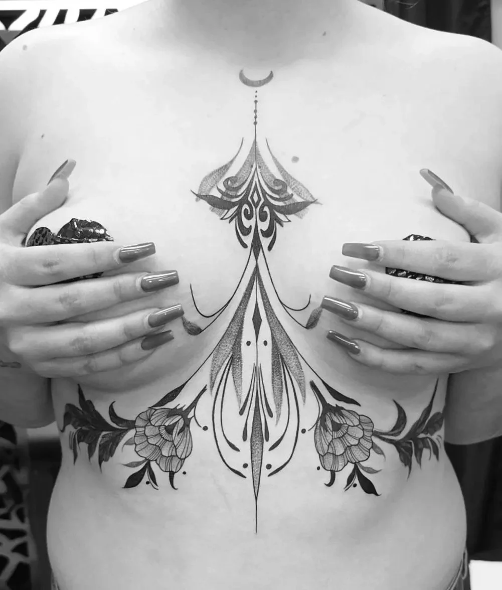 A person with an intricate symmetrical tattoo on their chest and abdomen, holding their breasts with hands that have painted nails.