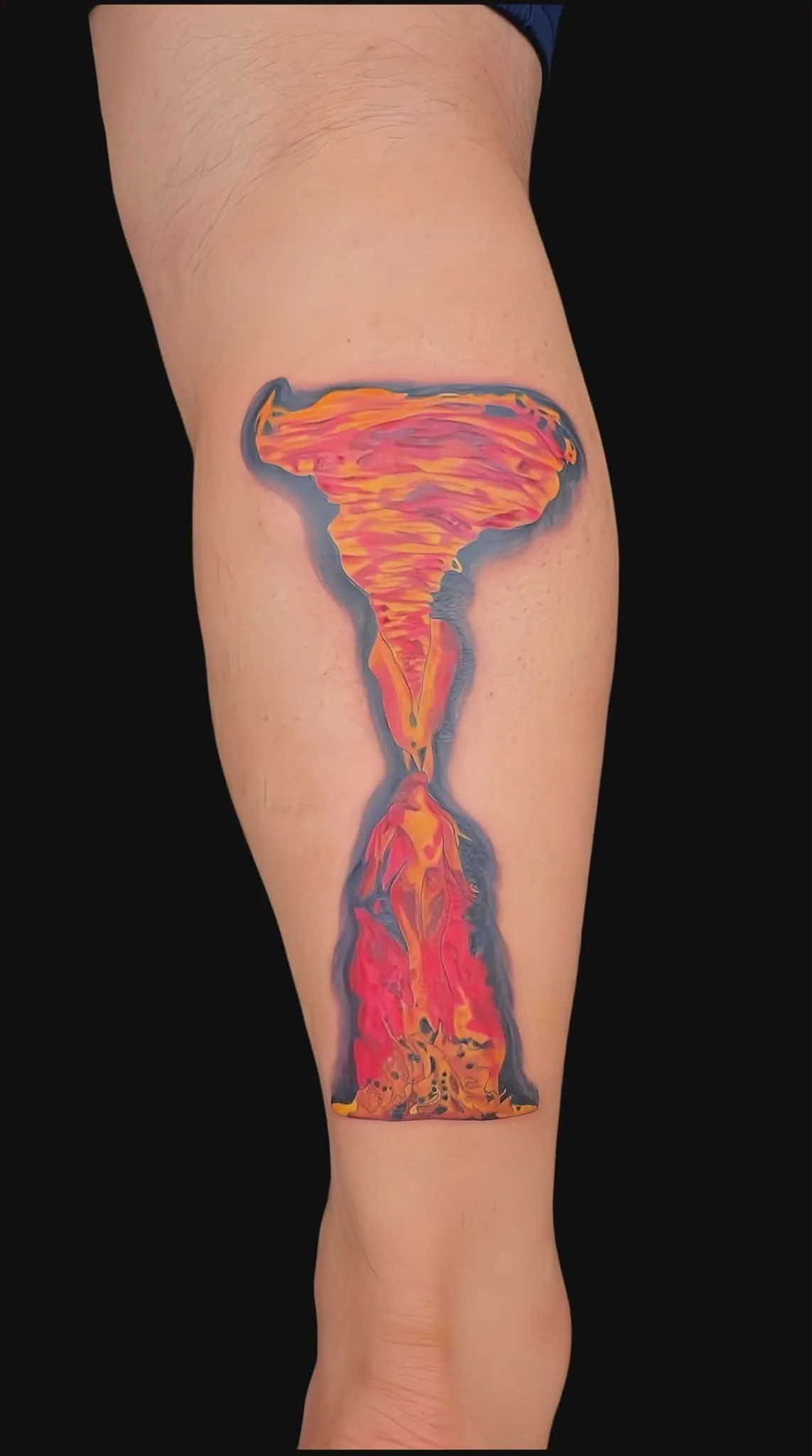 Colorful tattoo of a tornado with a fiery base on a person's calf.