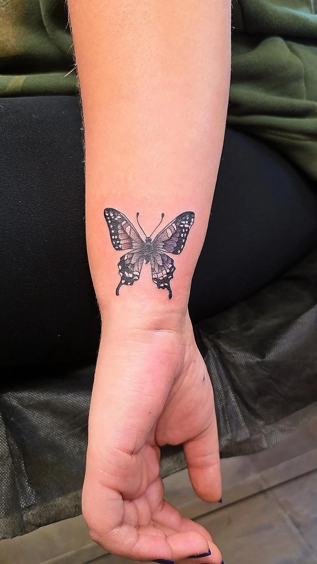 Tattoo of a butterfly on a person's forearm.