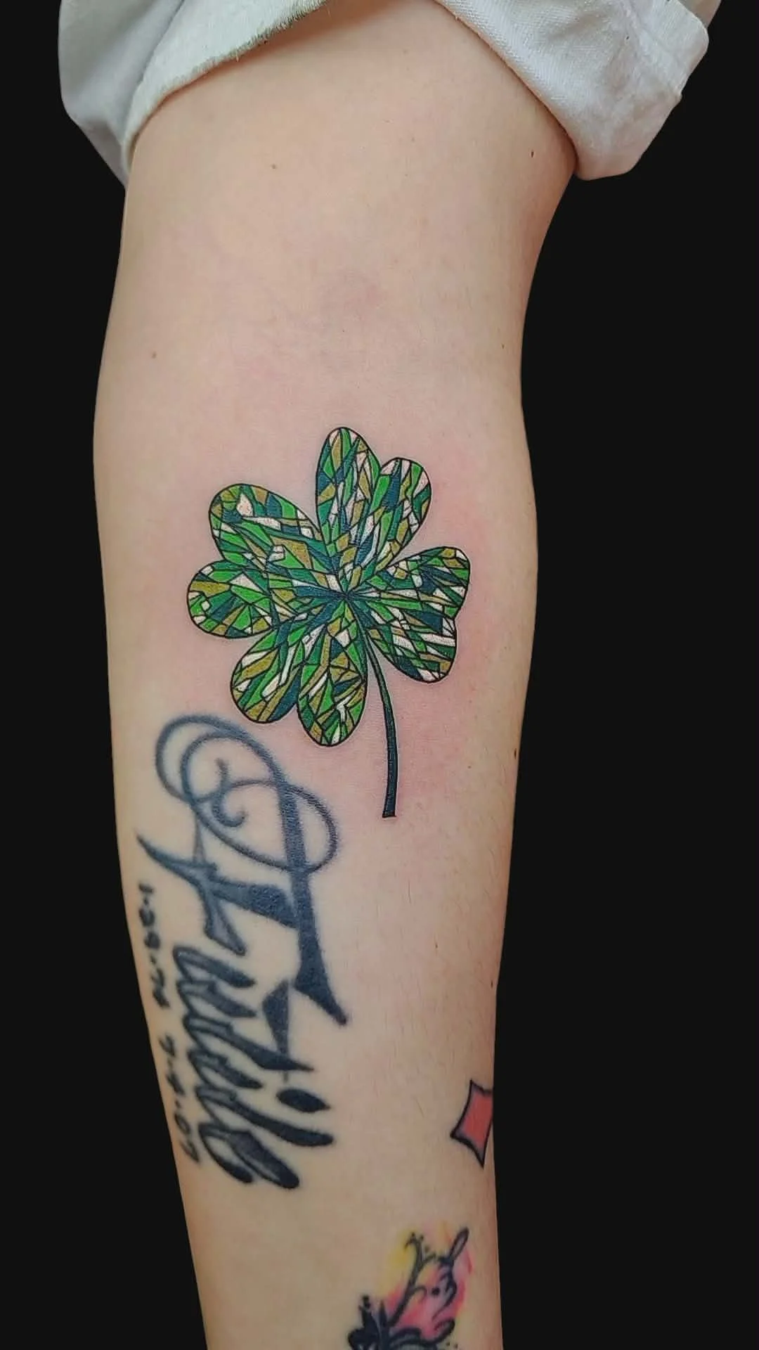 Tattoo of a stained glass style four-leaf clover on a person's arm.