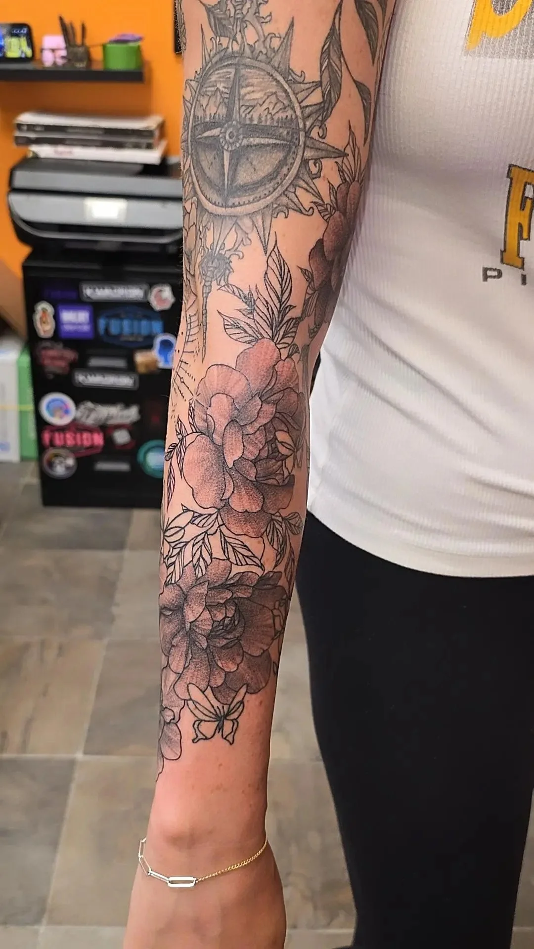 A person with a tattoo sleeve featuring a flower and butterfly design on their arm.