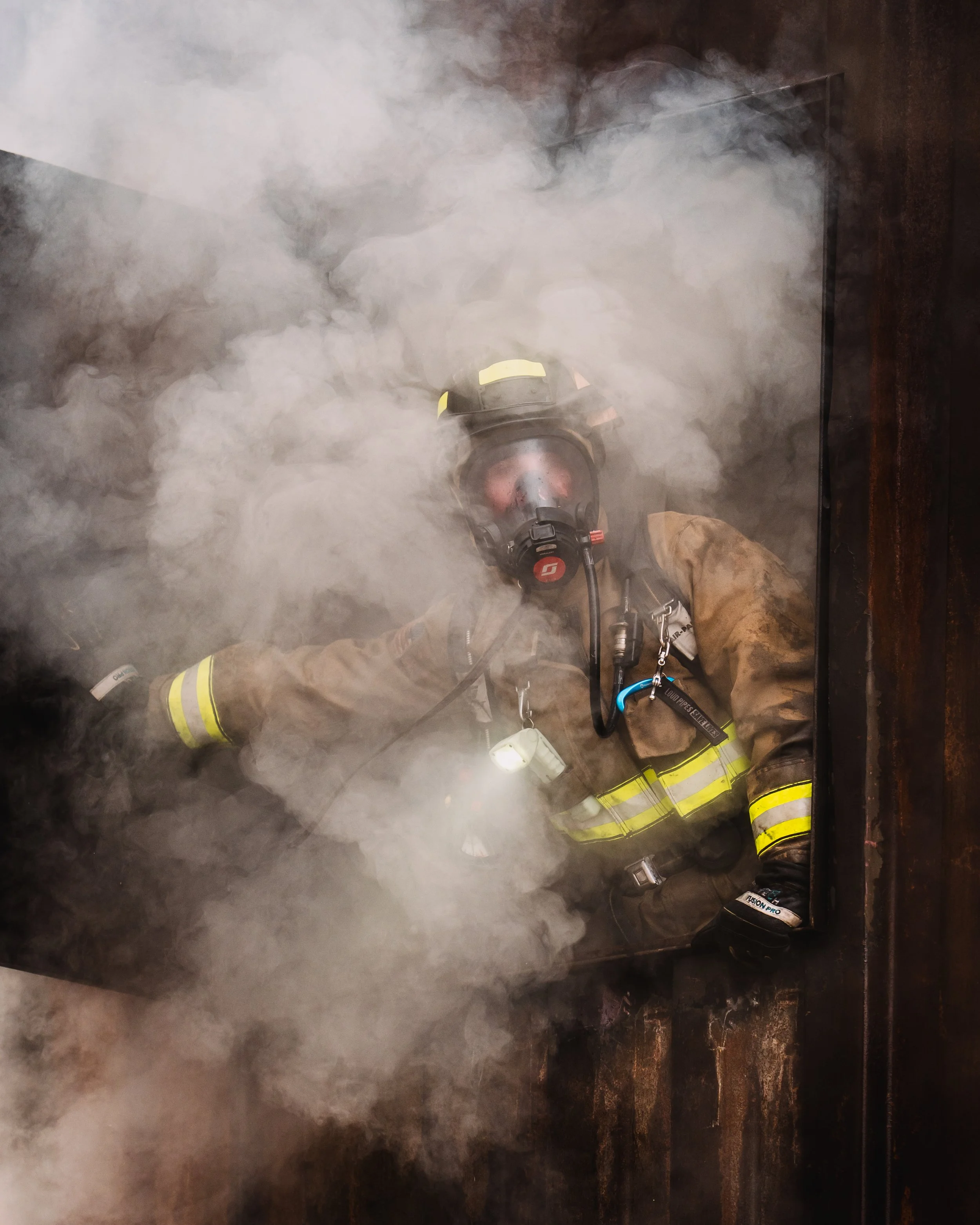 A firefighter looks out of the window full of smoke.