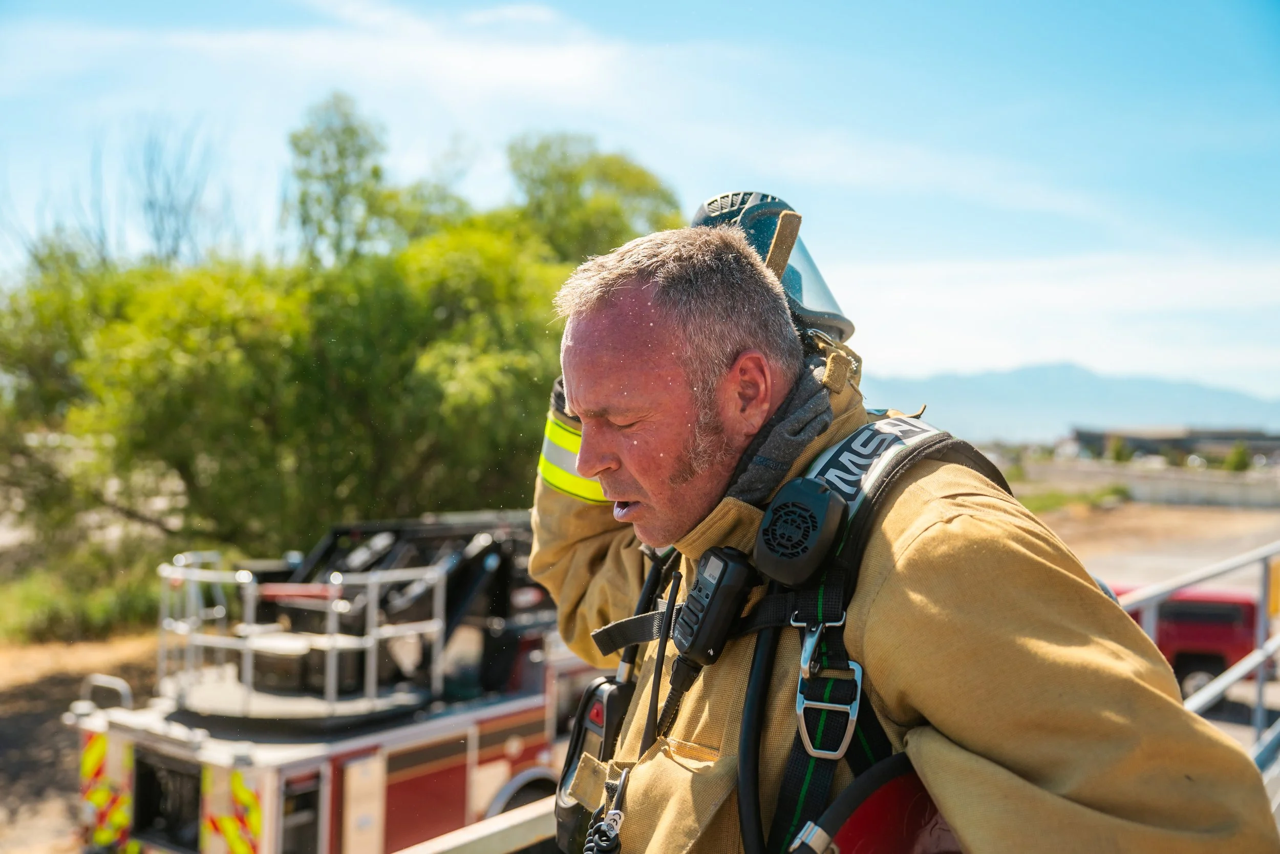 A firefighter takes off his respirator after a training scenario