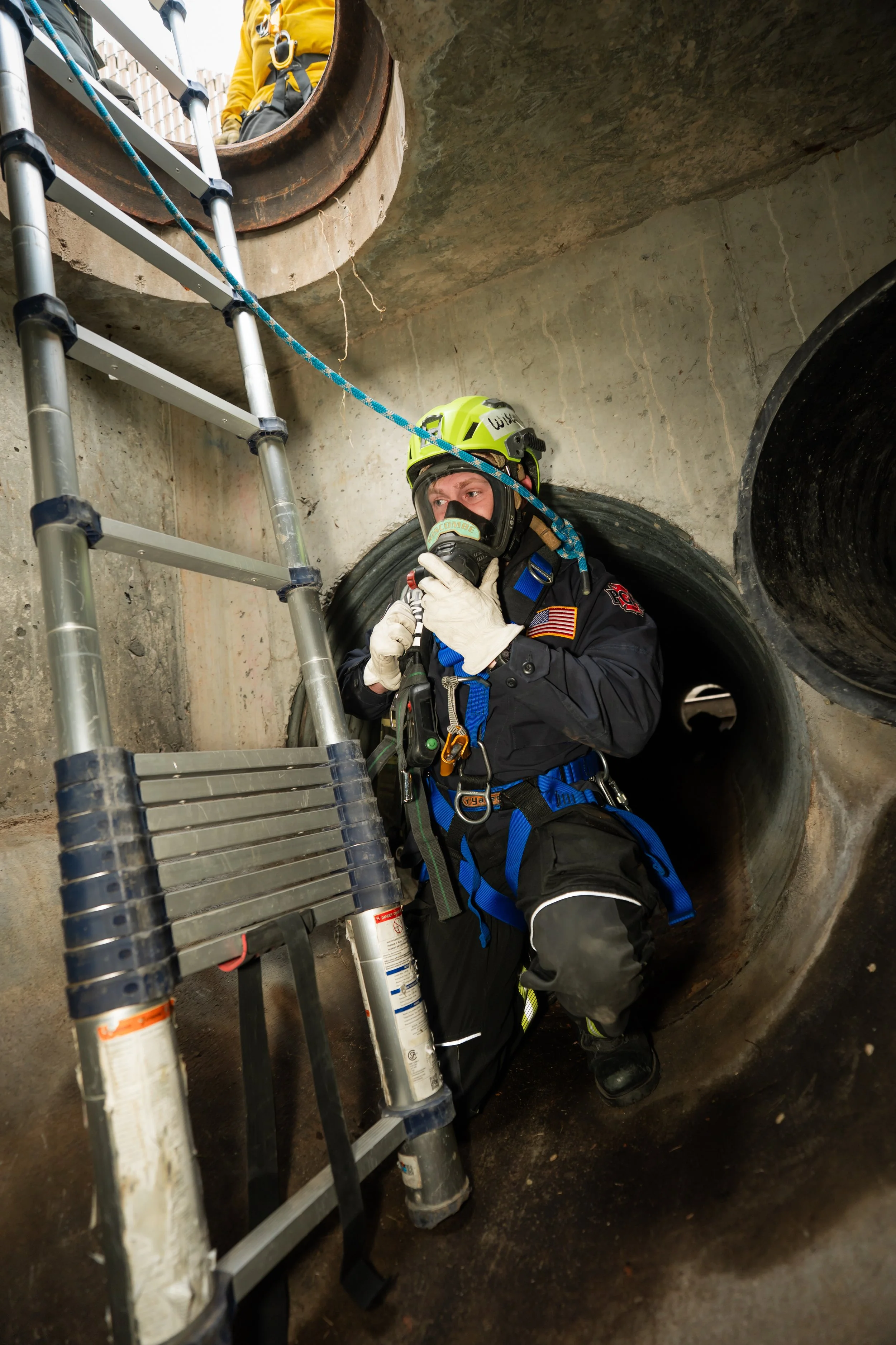 A firefighter gets his bearings after dropping into a sewer.