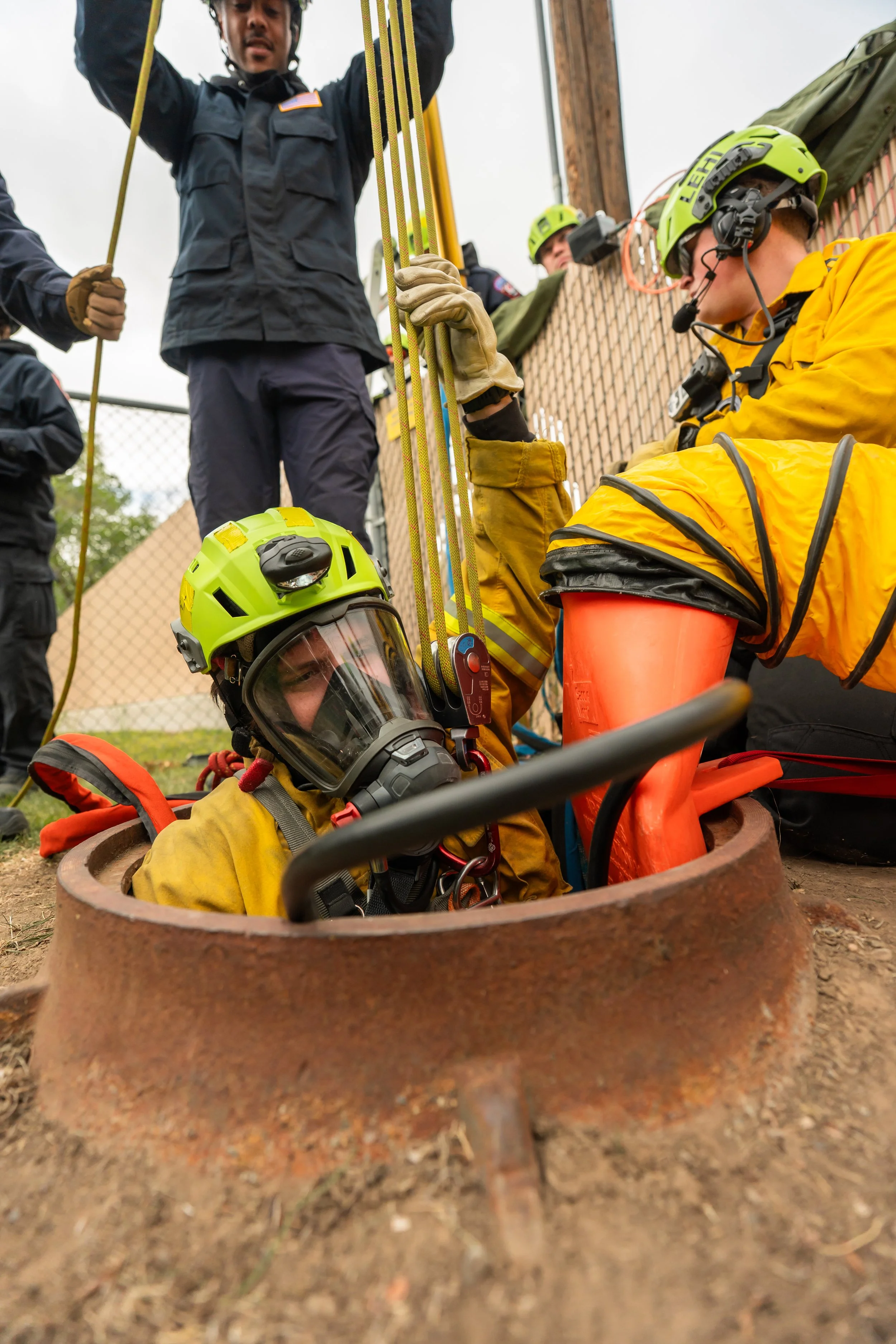 A firefighter gets lowered into a sewer.