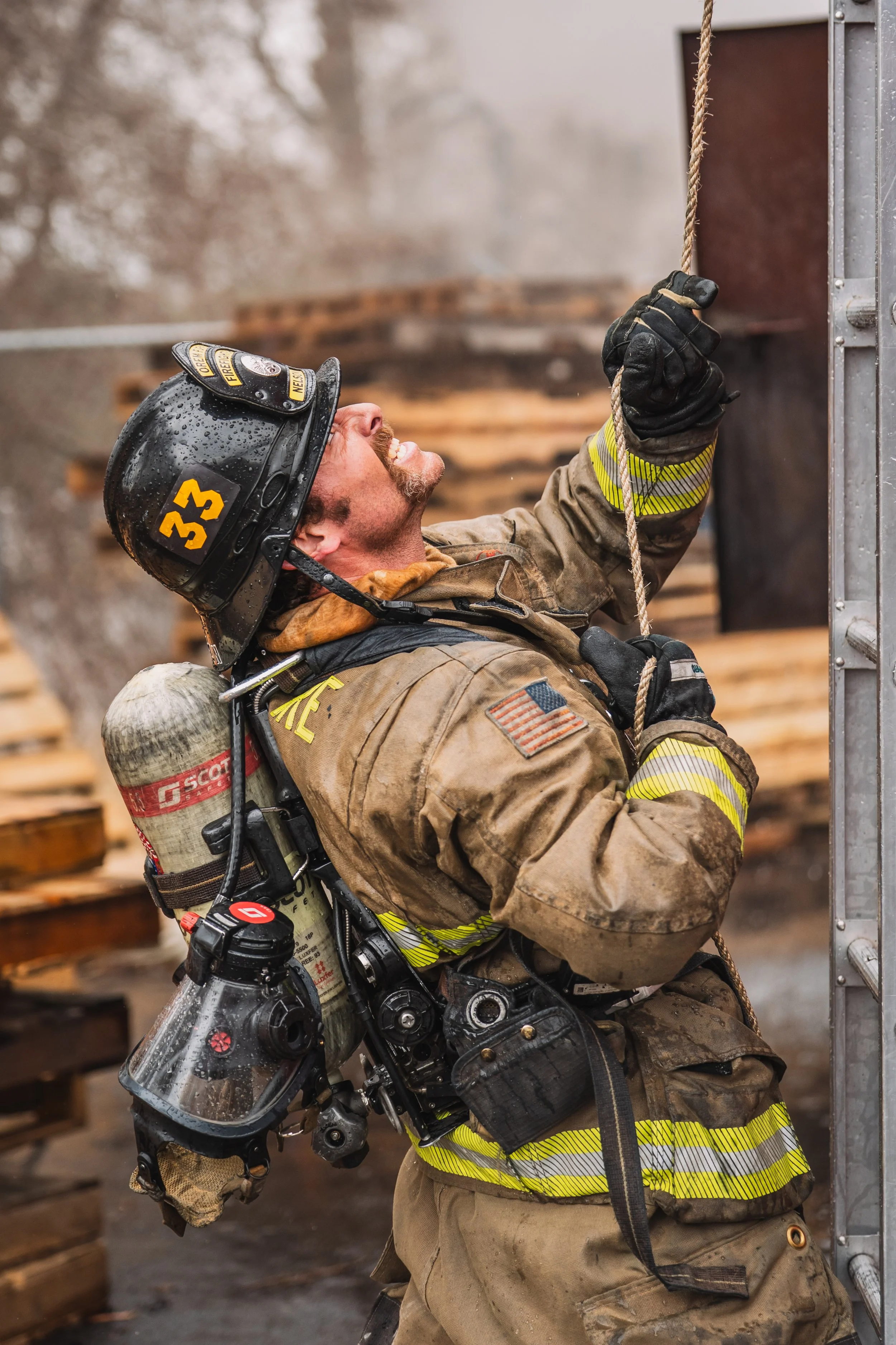 A firefighter fights the ladder as he gets sprayed in the face.