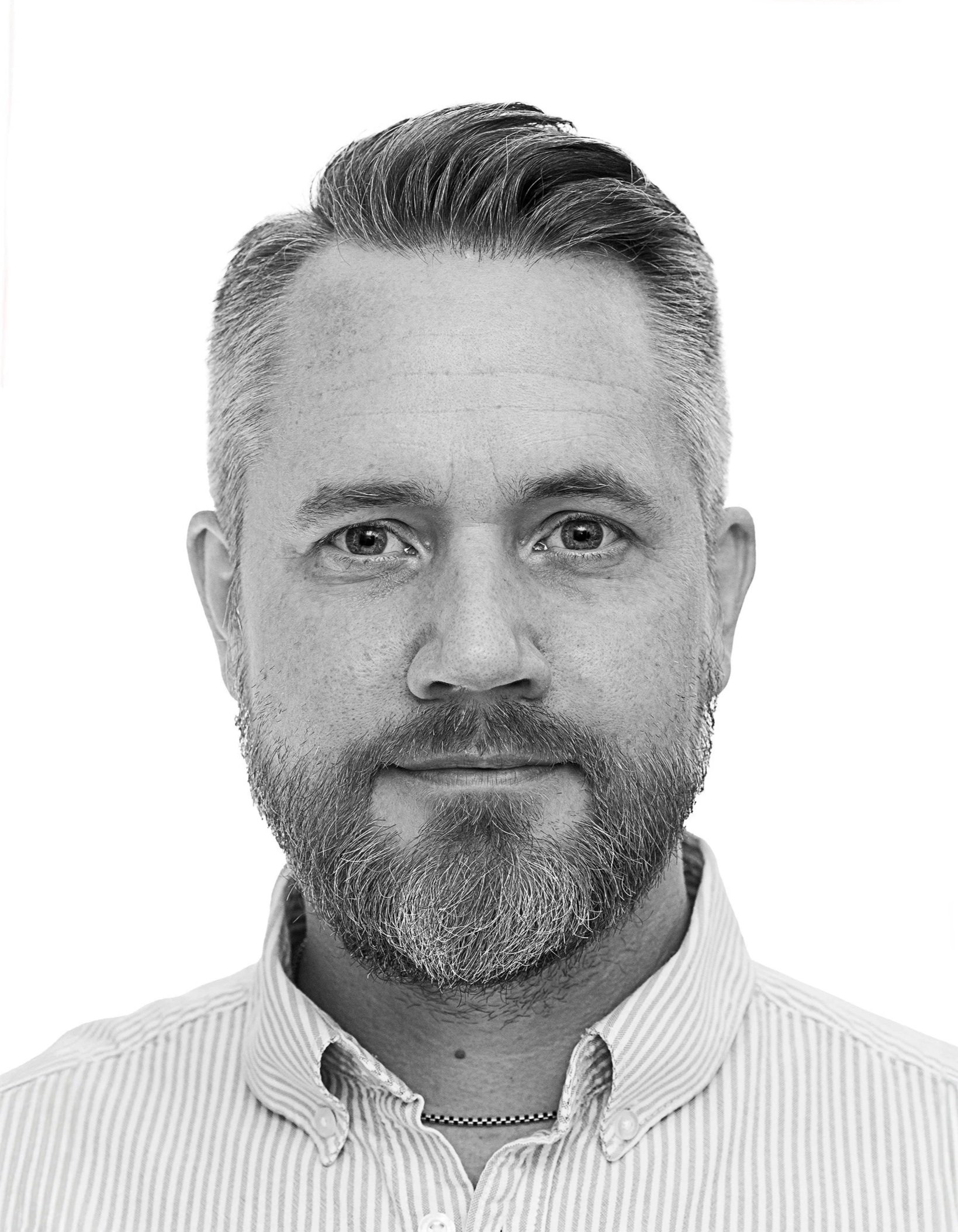 Svartvitt studioporträtt av Jim Sjöholm mot vit bakgrund