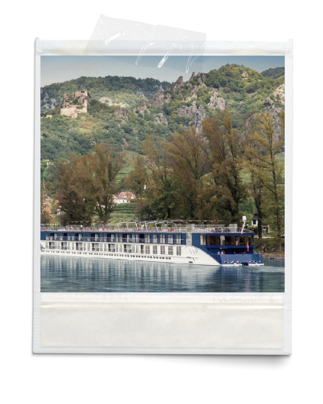 Photograph of a cruise ship on a river with a green hill and trees in the background.