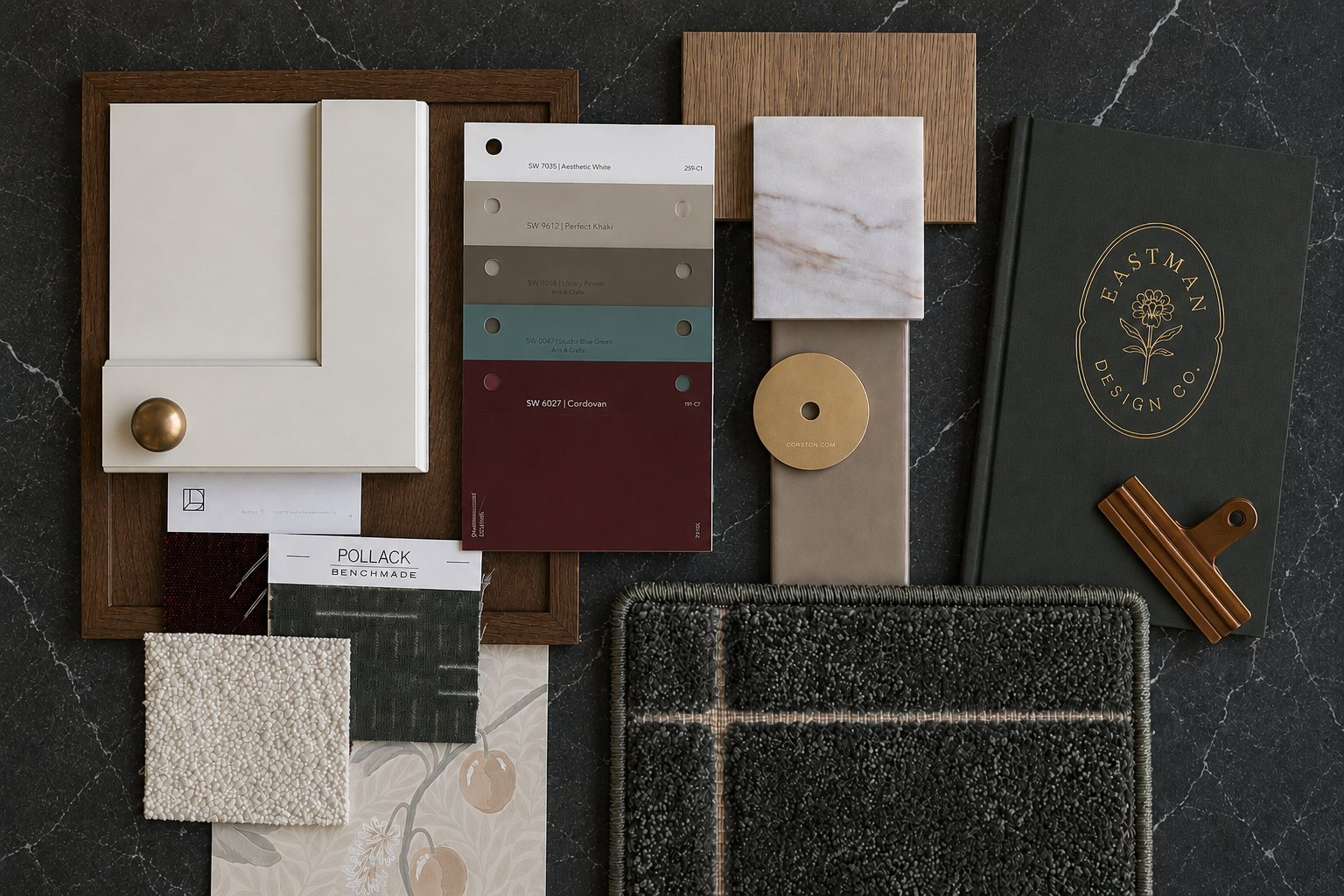 Interior design sample materials arrangement with paint swatches, tiles, fabric samples, and a notebook on a black marble surface.