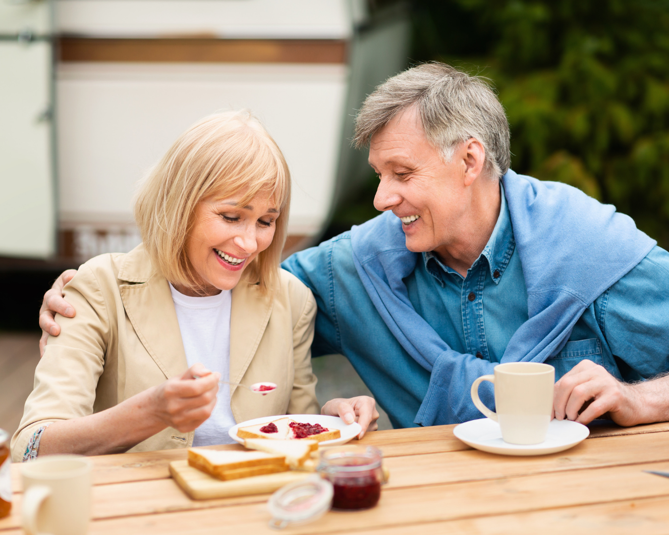 A woman in her fifties and her husband laughing together outdoors, relaxed and enjoying time together.