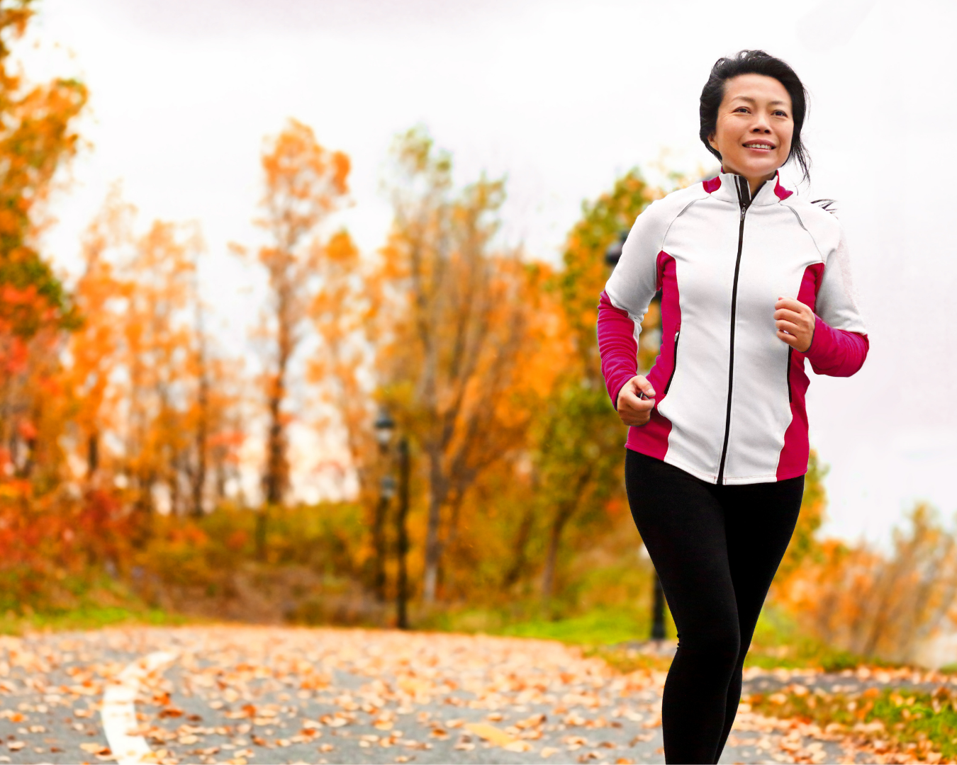 A woman in her forties jogging outdoors on a fall morning, moving with energy and strength.