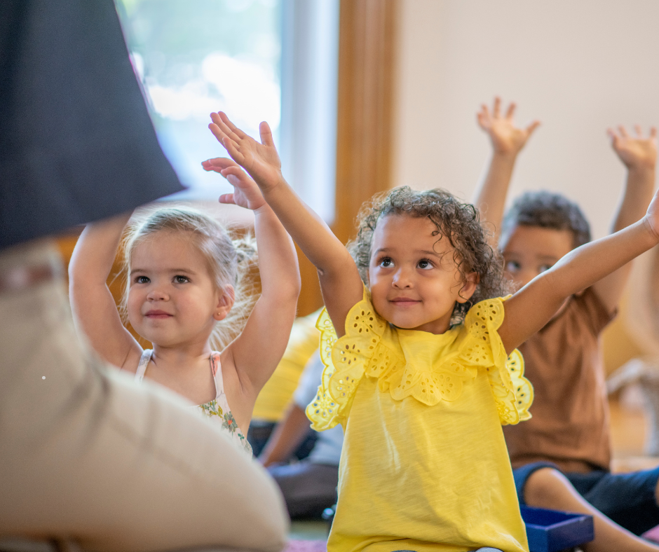 Children in a classroom raising their hands during a lesson or activity.