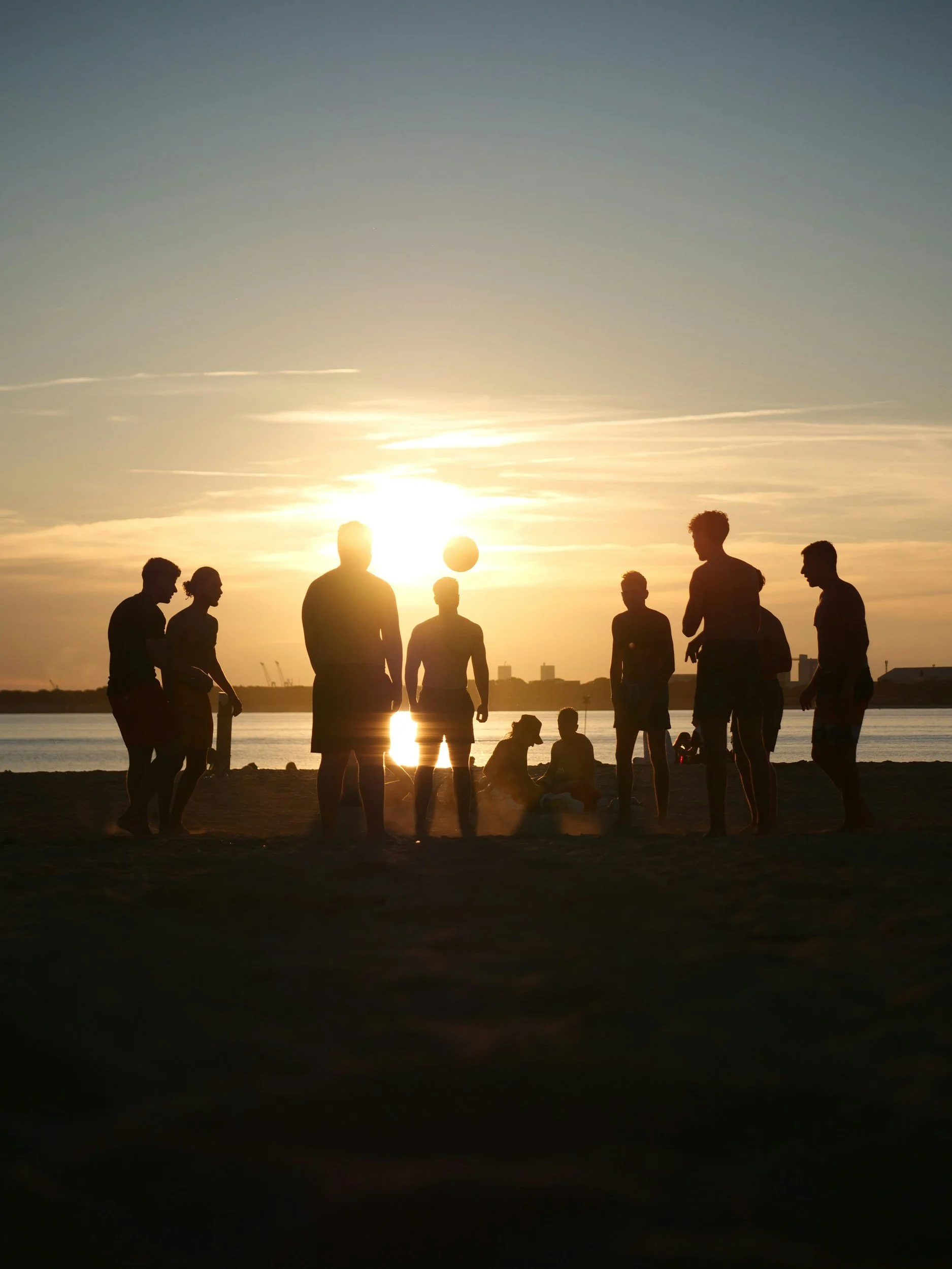 Silhouettes of seven people and a dog playing volleyball on a beach during sunset. Samara, Costa Rica