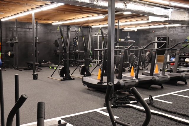Gym equipment including treadmills, weight machines, a rowing machine, and cones in a workout room.