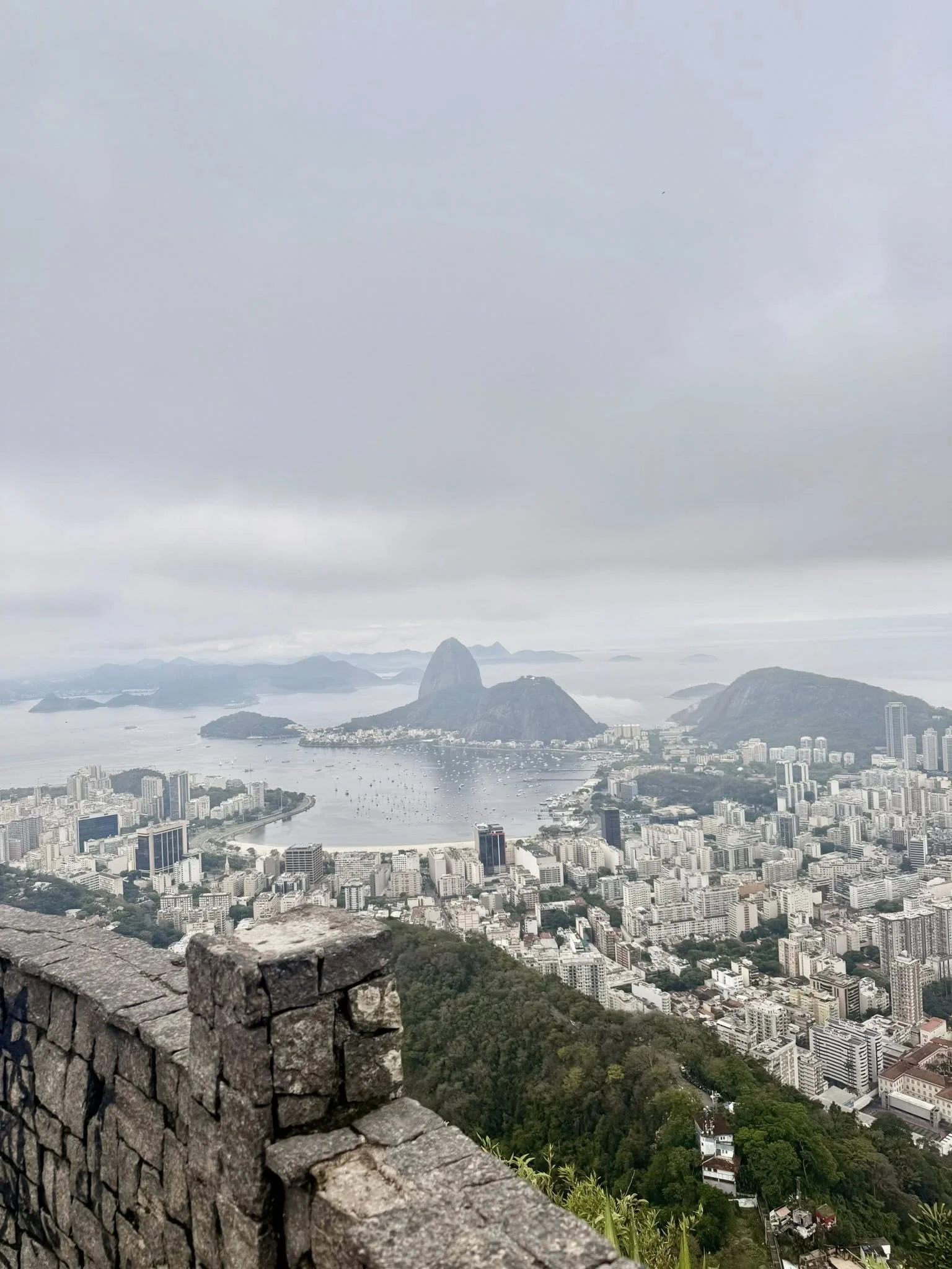 Cityscape of Rio de Janeiro, Brazil, with Sugarloaf Mountain in the background and a cloudy sky overhead.