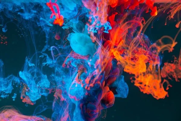 Colorful swirling ink or dye in water with blue and orange hues