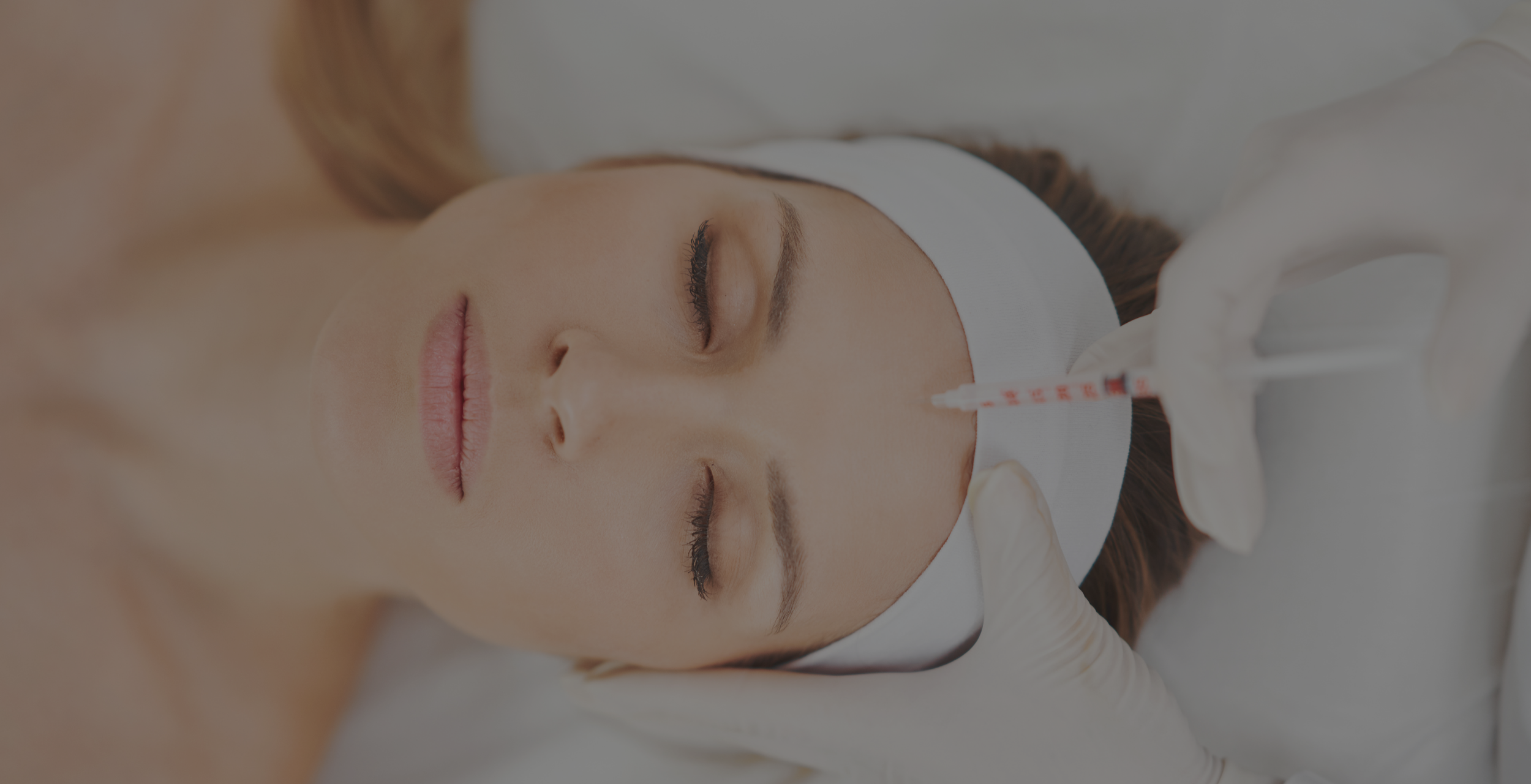 Close-up of a woman lying on a medical bed with a bandage on her head, her eyes closed, and a medical tube attached to her nose.