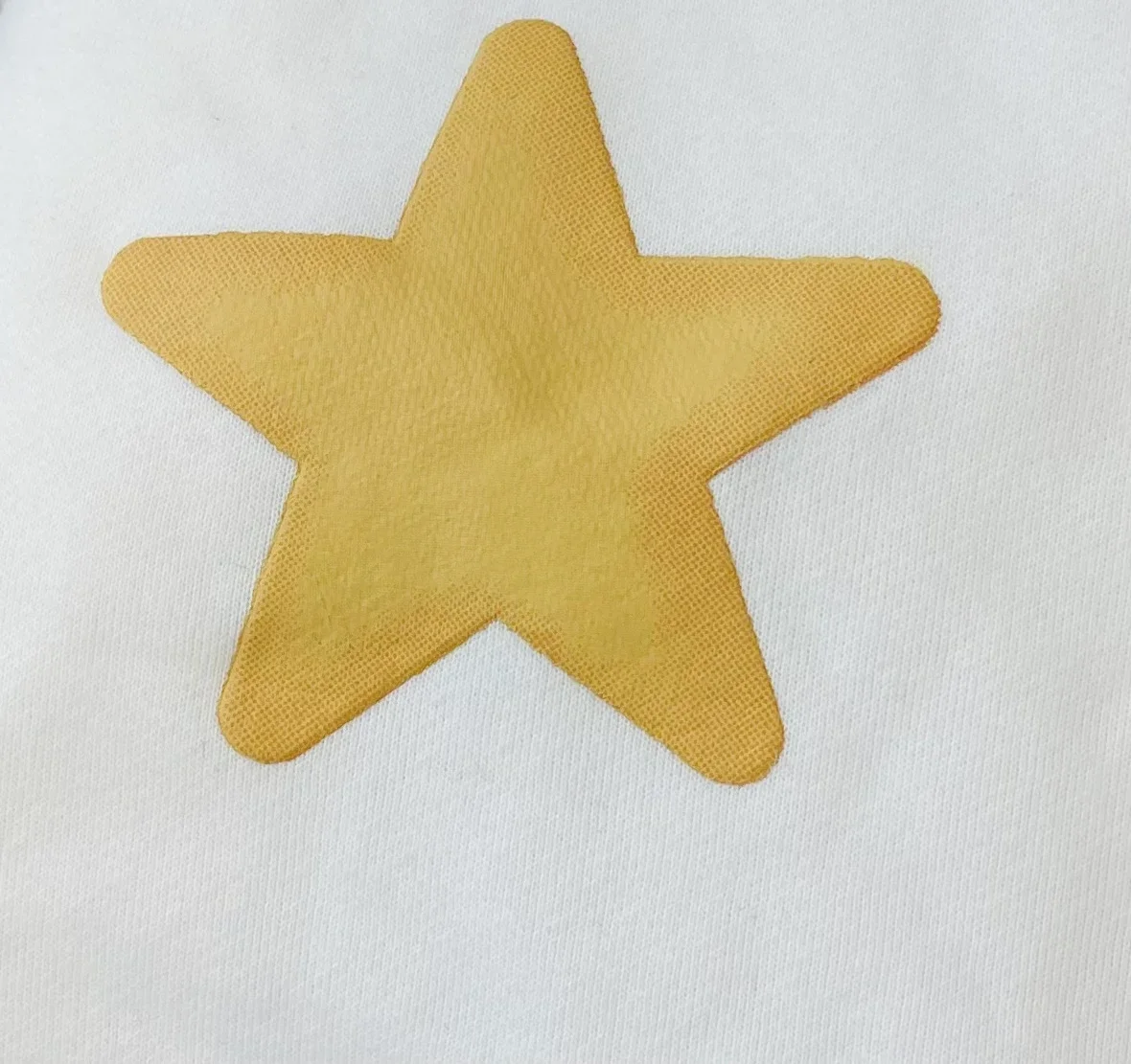 Close-up of the gold puff star on white cotton.