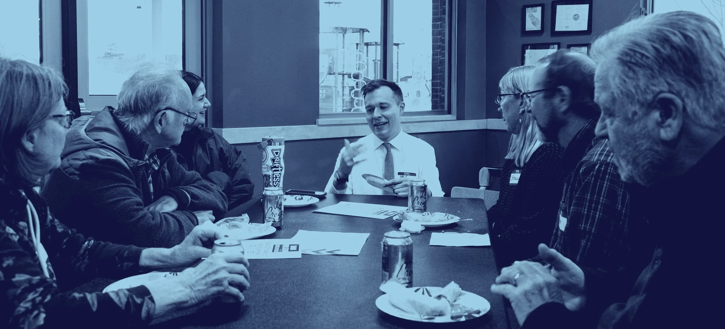 Dan Wilson talking to a table of Winona County residents that are smiling.