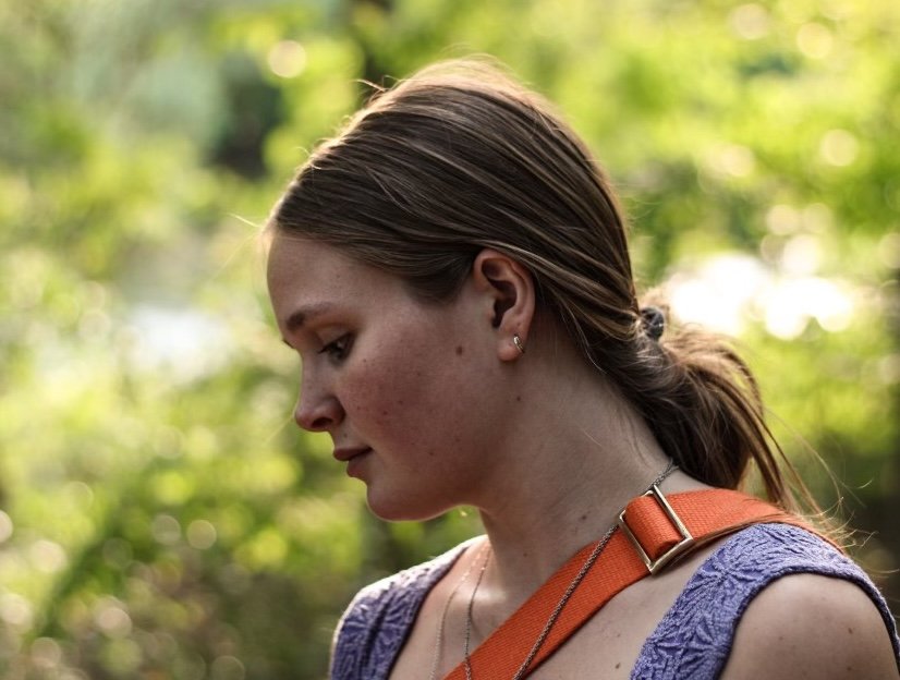 Zelda Cherner's (the artist) side profile with a green forest backdrop
