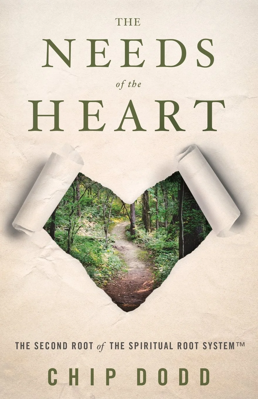 Book cover titled 'The Needs of the Heart' by Chip Dodd featuring a torn paper revealing a forest path.